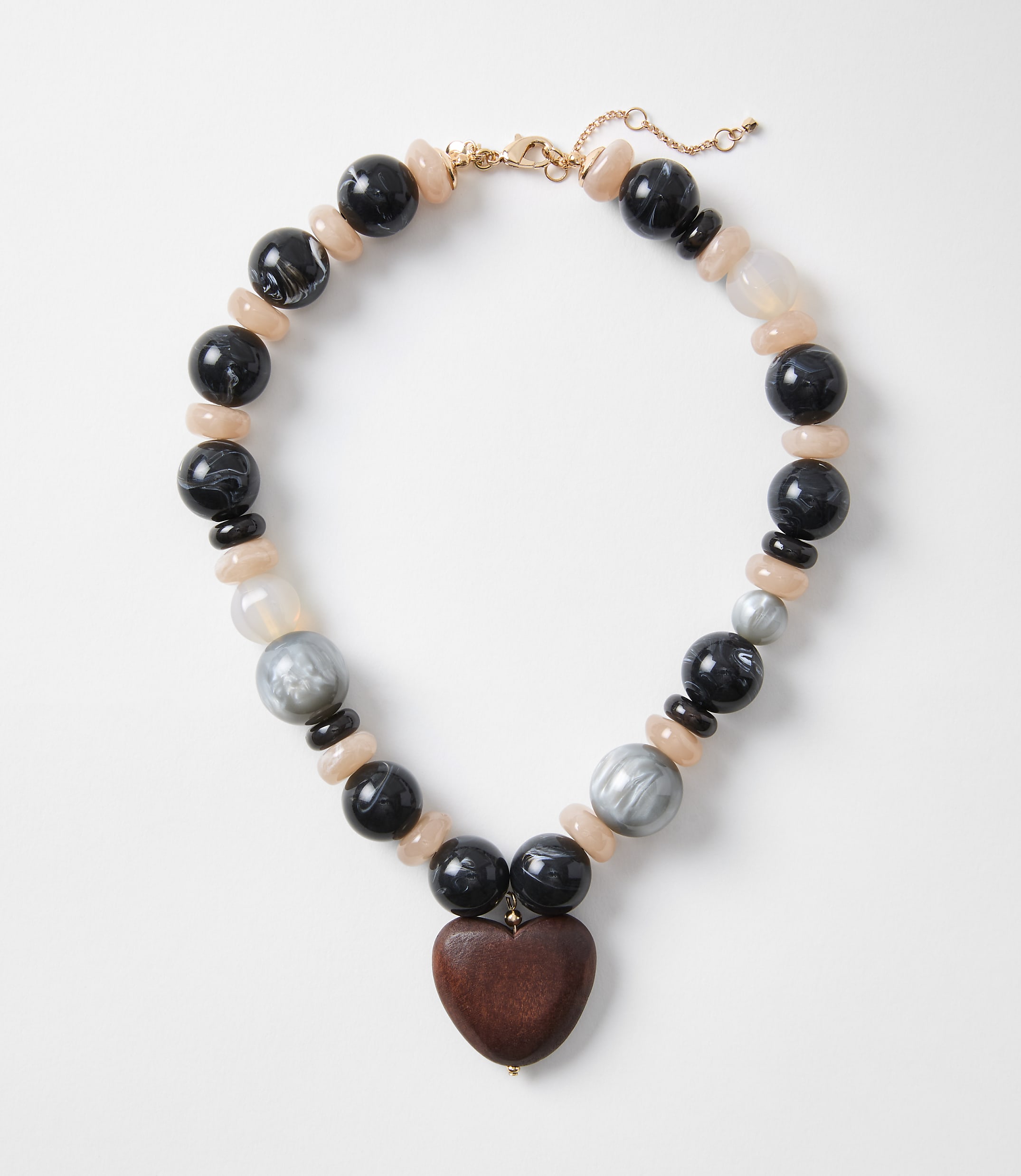 A chunky necklace with a wooden heart pendant rests on a plain white background.