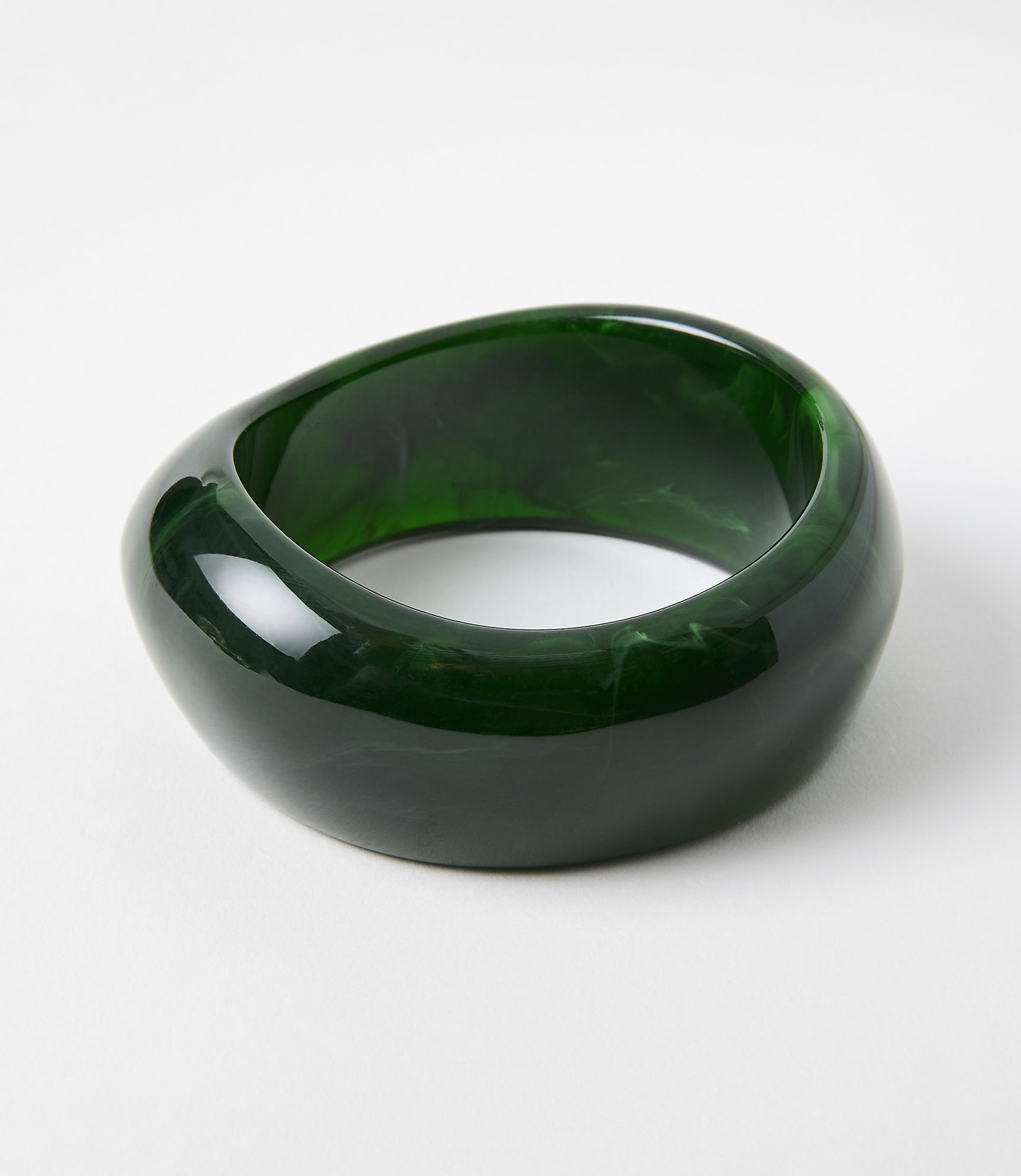 A glossy, dark green, irregularly shaped bangle rests on a plain white background.
