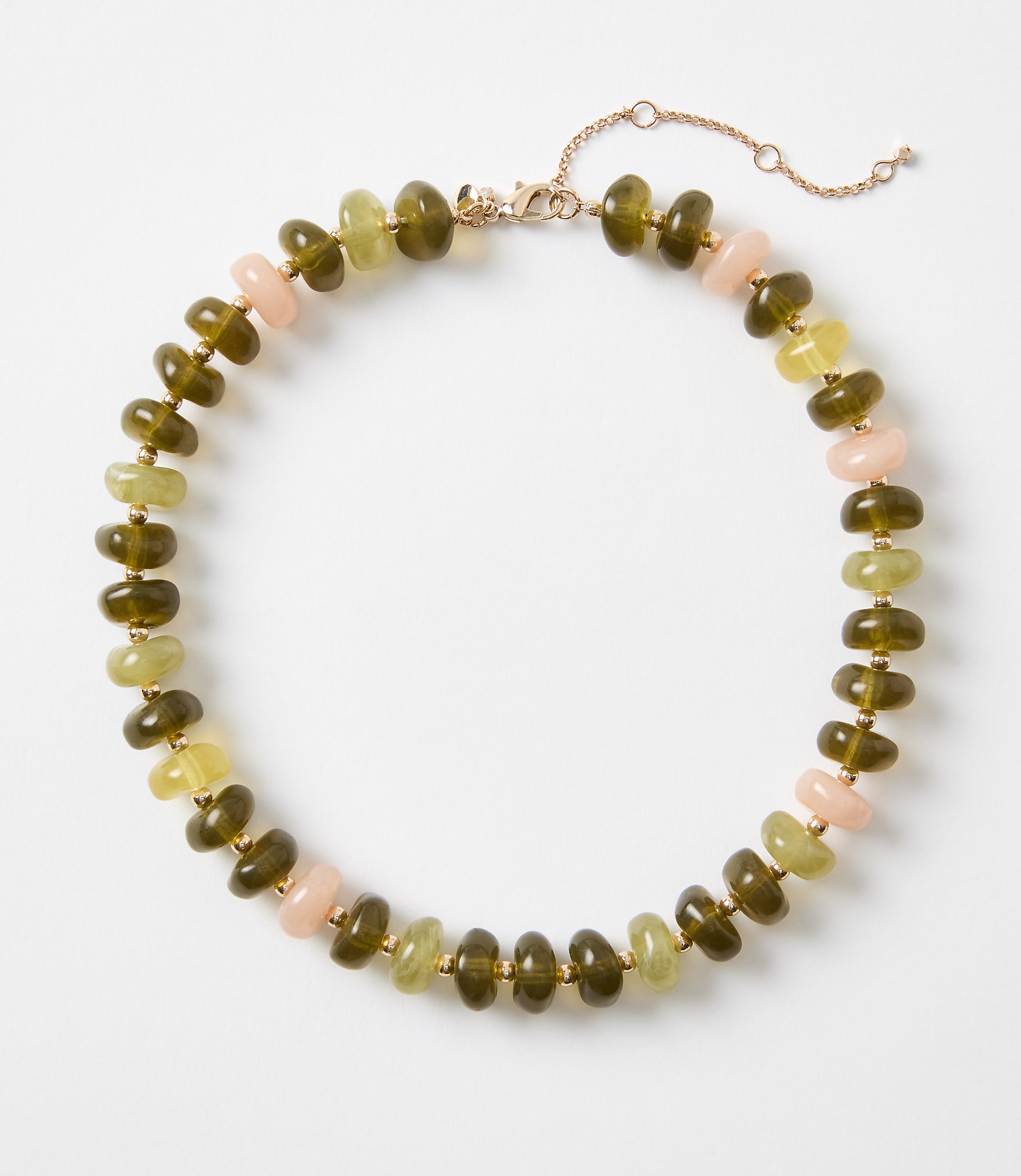 A beaded necklace with olive green, pale yellow, and pink beads is laid out on a plain white background.