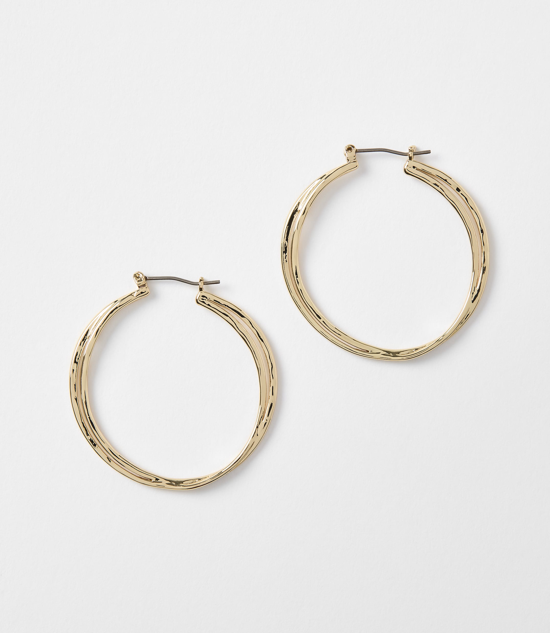Two textured gold hoop earrings rest on a plain white background.