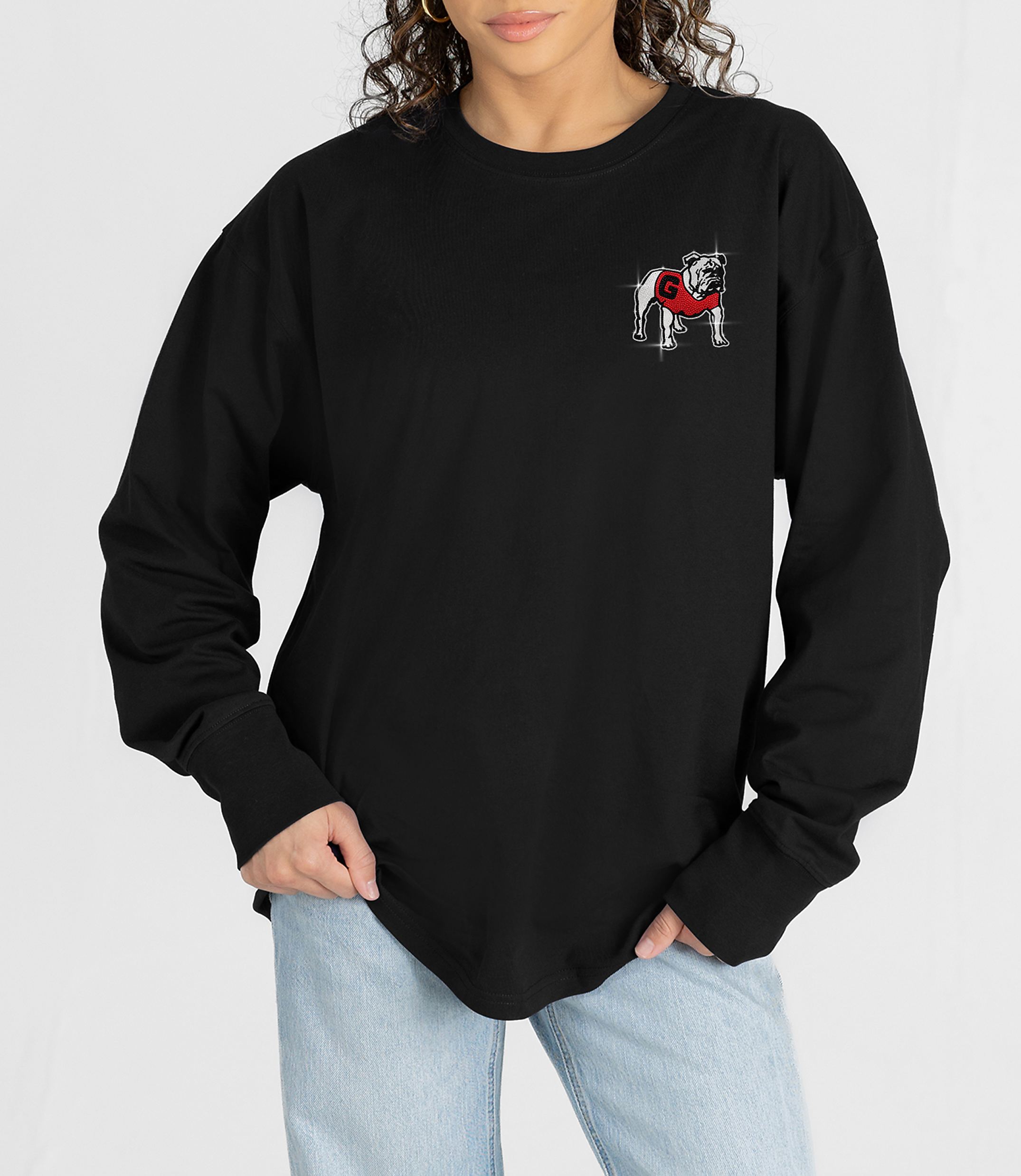 A person in a black long-sleeved shirt with a bulldog graphic on the chest stands against a white background.