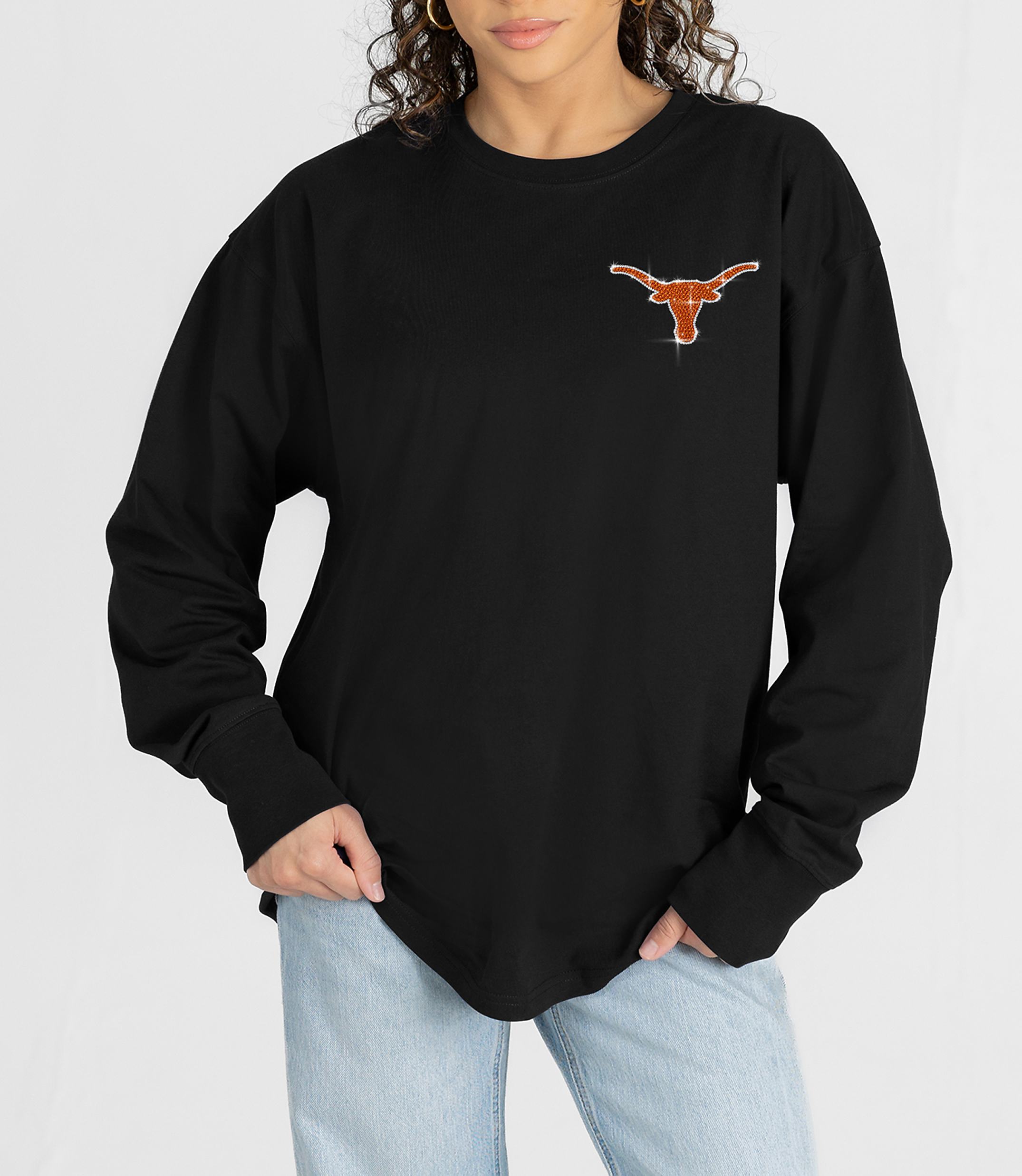 A person in a black long-sleeved shirt with a sparkly Texas Longhorns logo on the chest stands against a plain white background.
