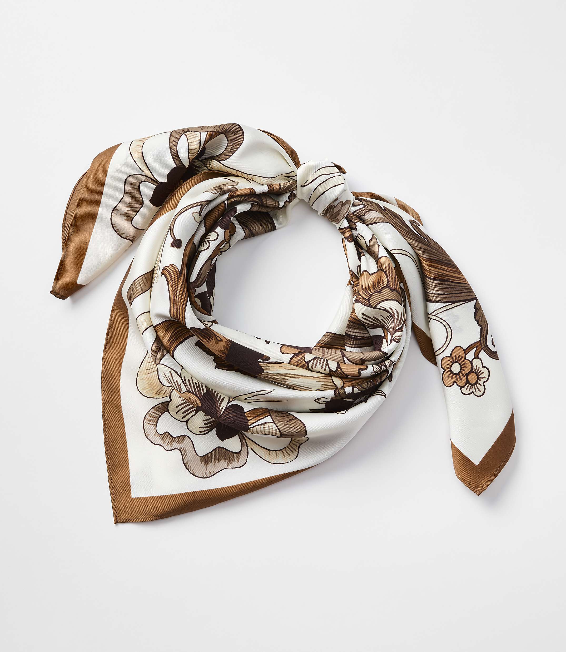 A silk scarf with a floral pattern in shades of brown and white is tied in a knot against a plain white background.