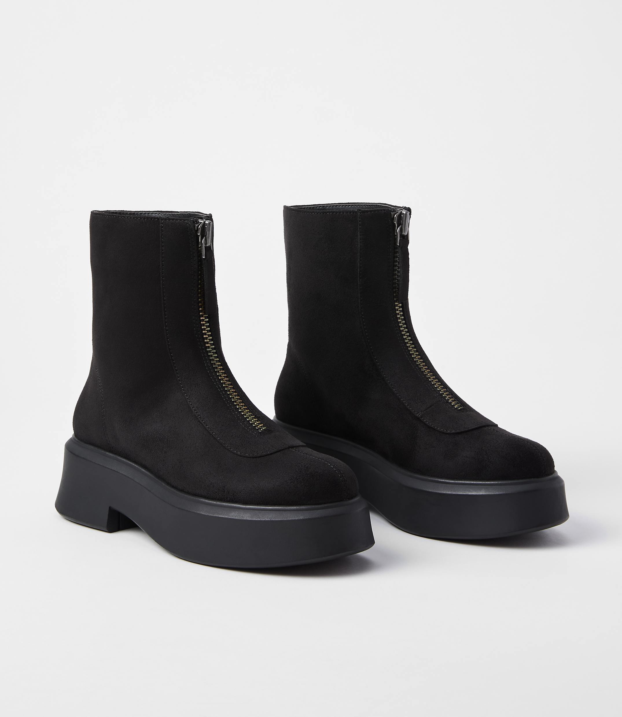 A pair of black, zip-front platform boots rests on a plain white background.