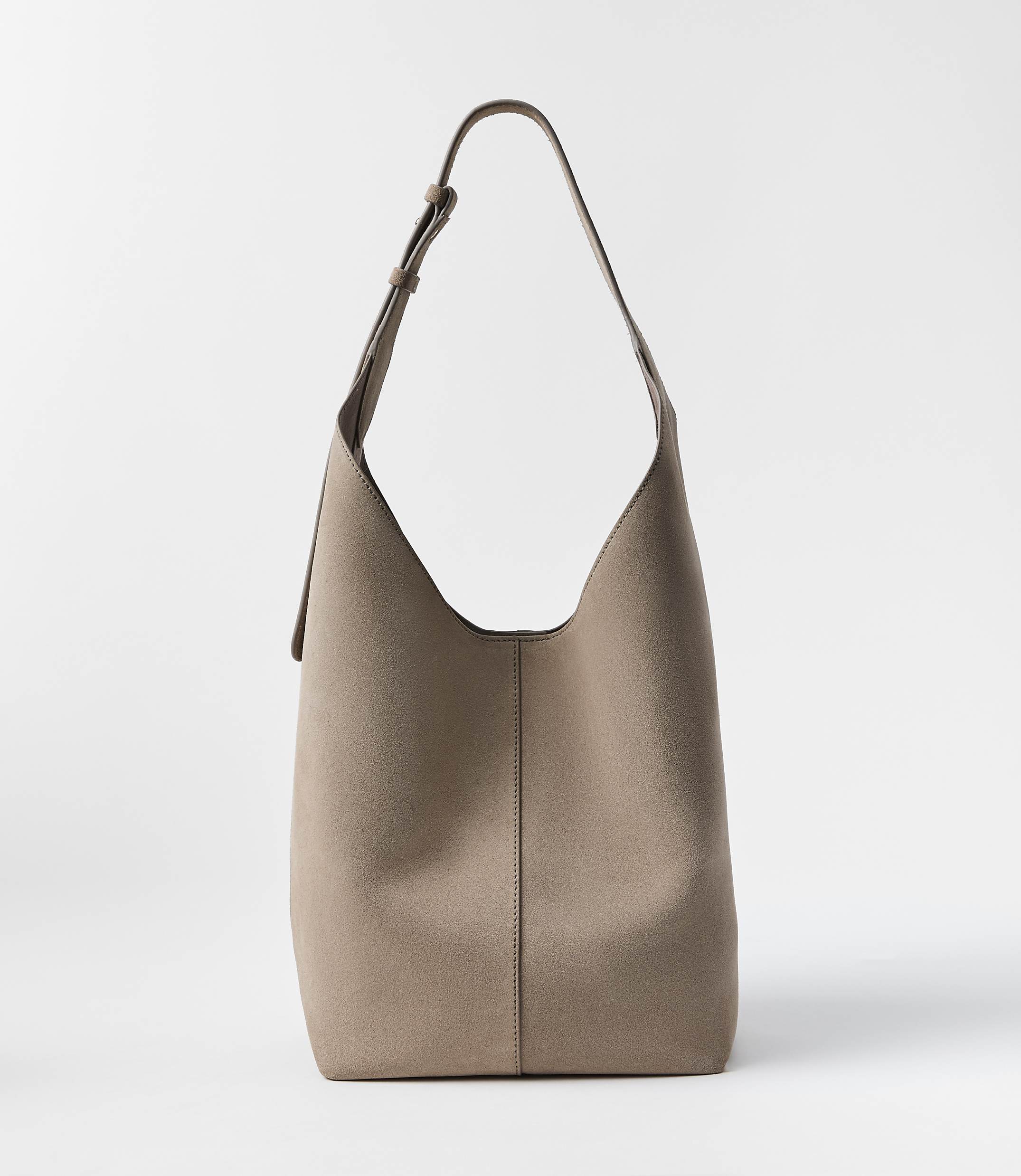 A taupe leather hobo bag with a single strap stands against a plain white background.