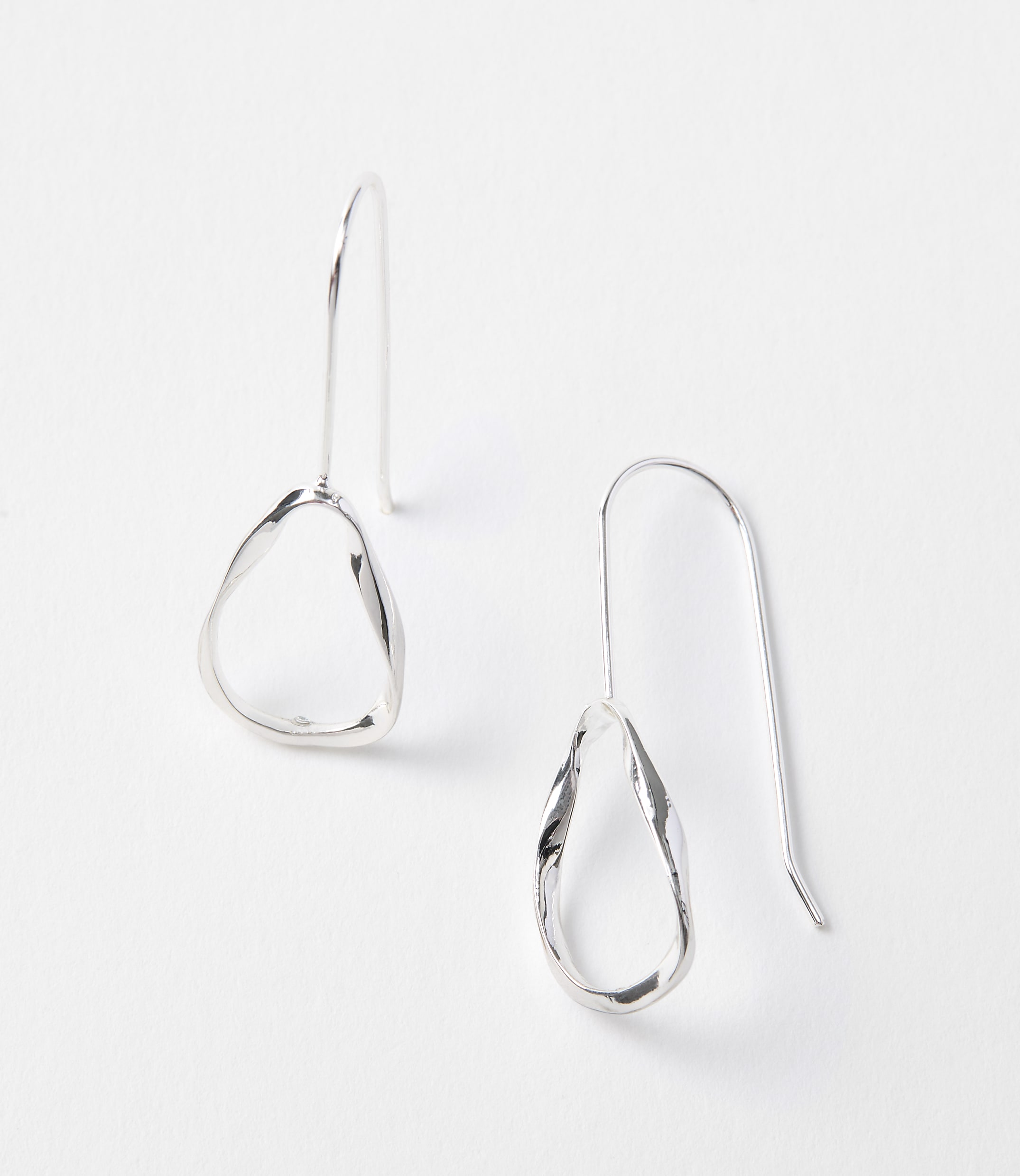 Two abstract, silver drop earrings with organic shapes hang against a plain white background.