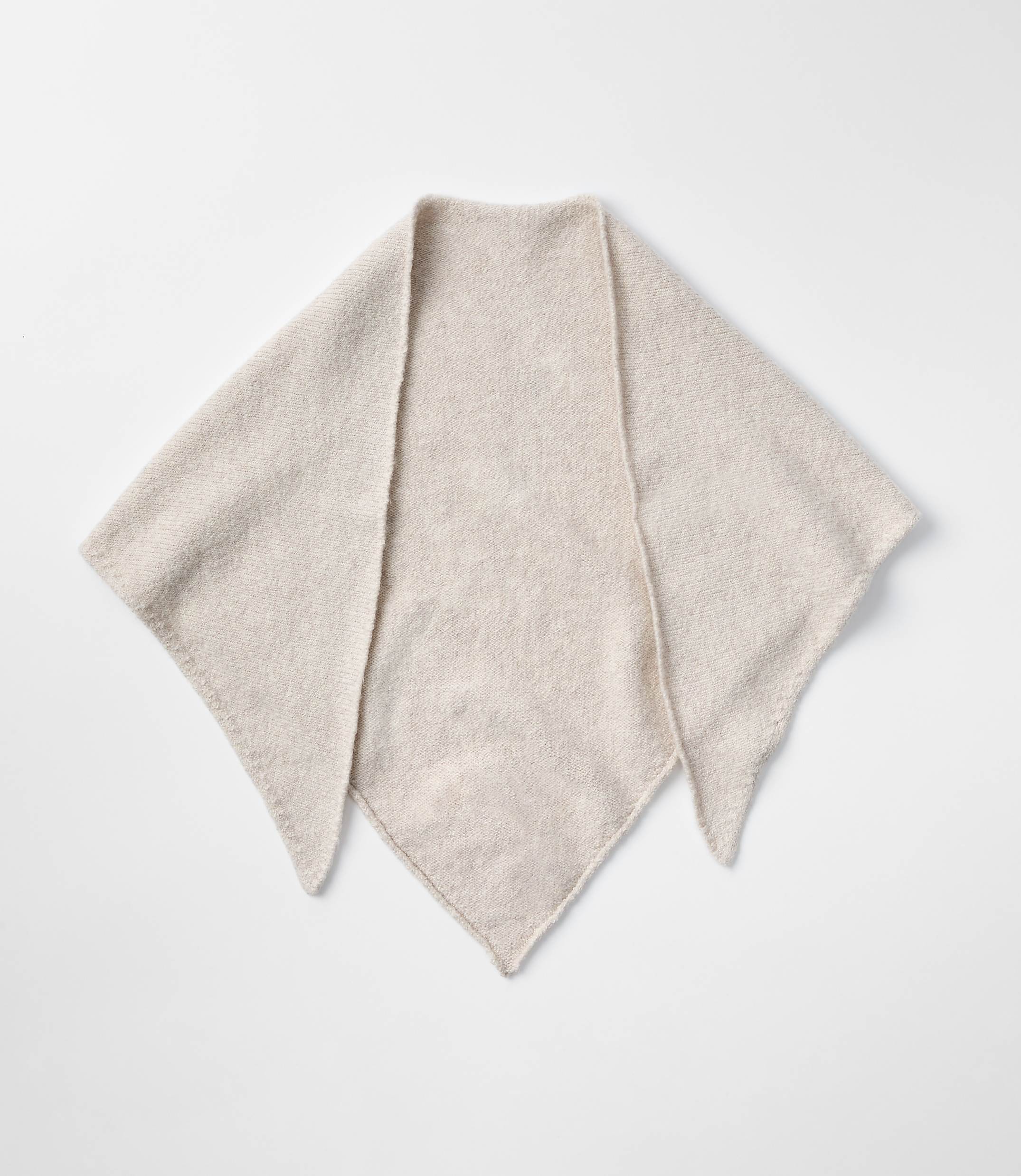 A light-colored, fuzzy triangular scarf lies flat against a plain white background.