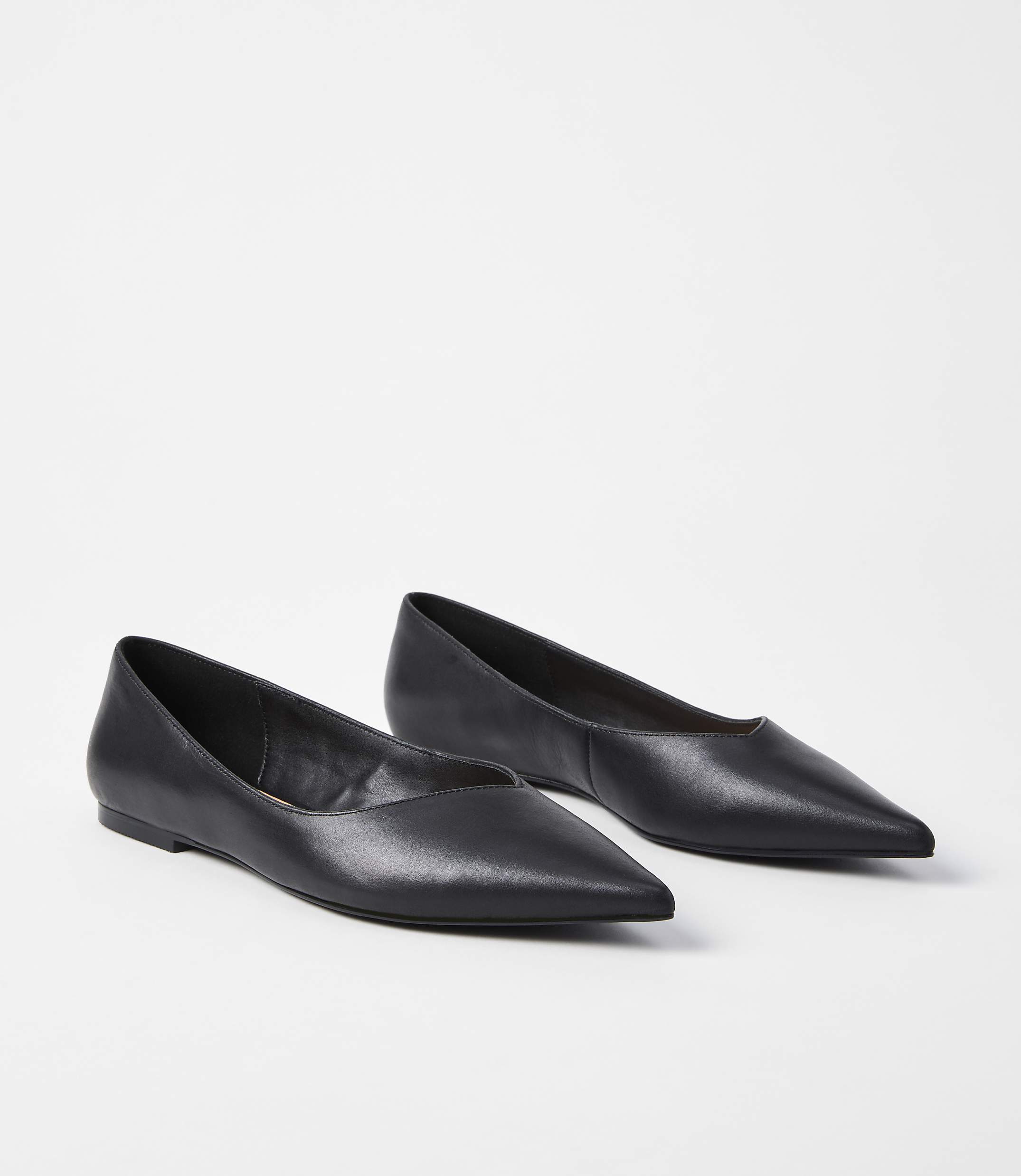A pair of black pointed-toe flats rests on a plain white background.