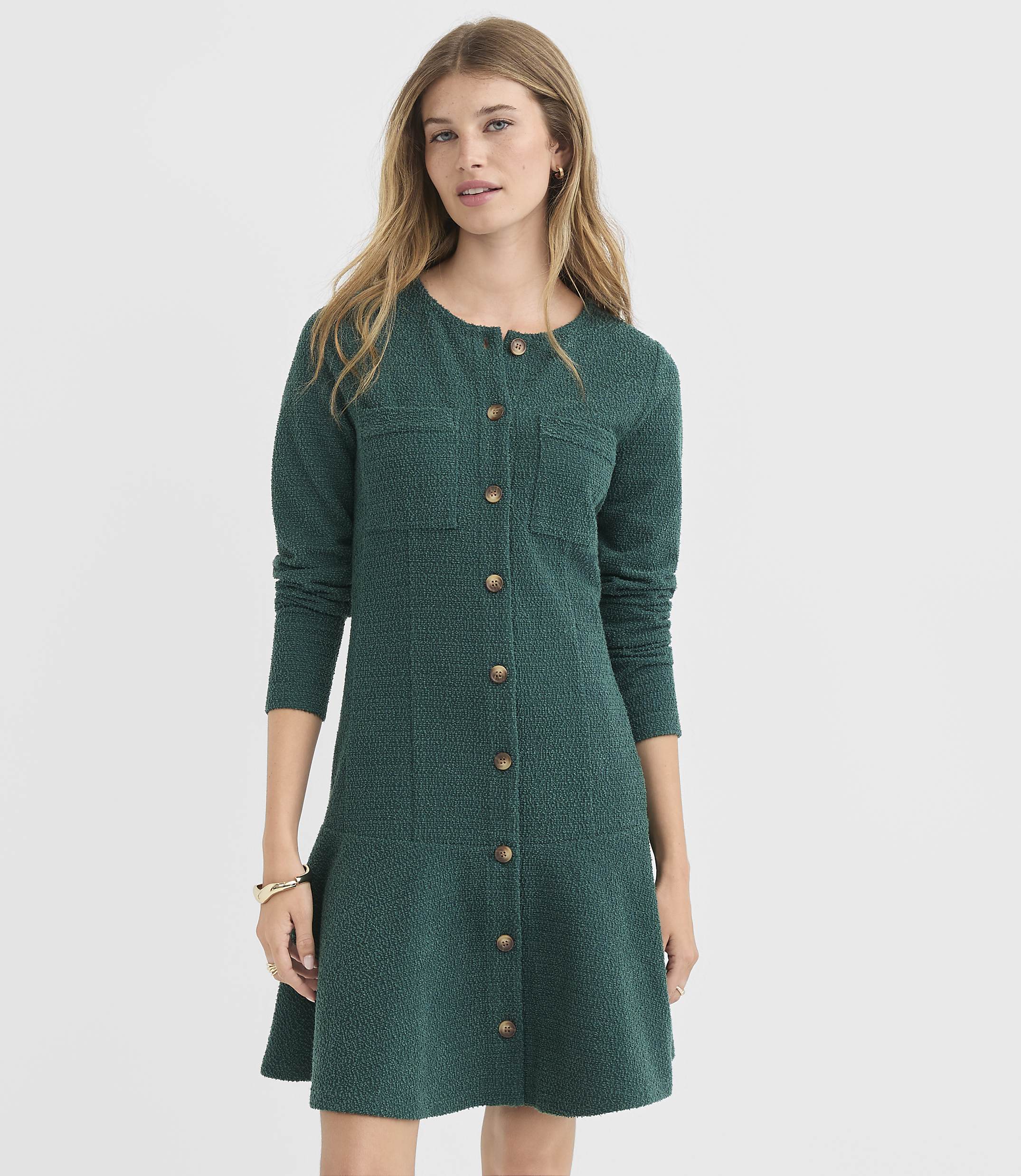 A woman in a green textured dress stands against a plain white background.