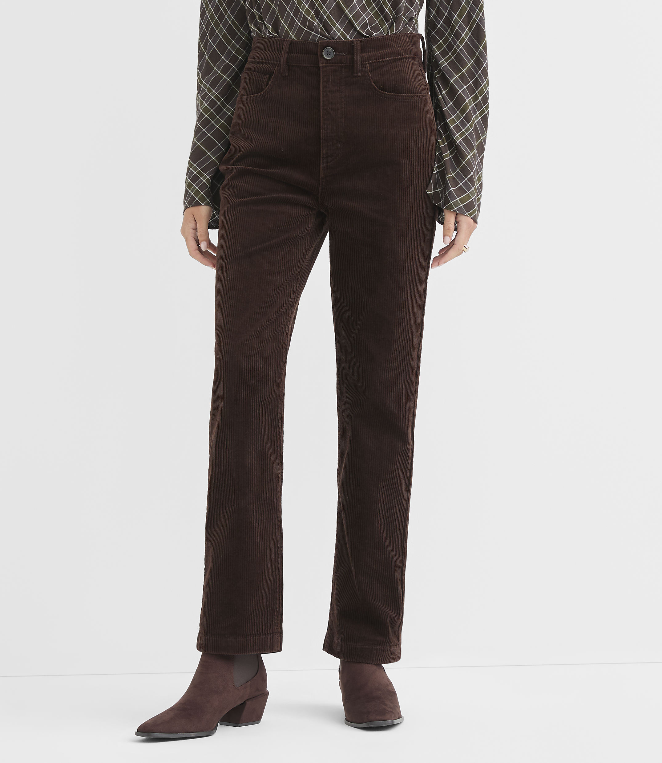 A person stands in brown corduroy pants and boots against a plain white background.