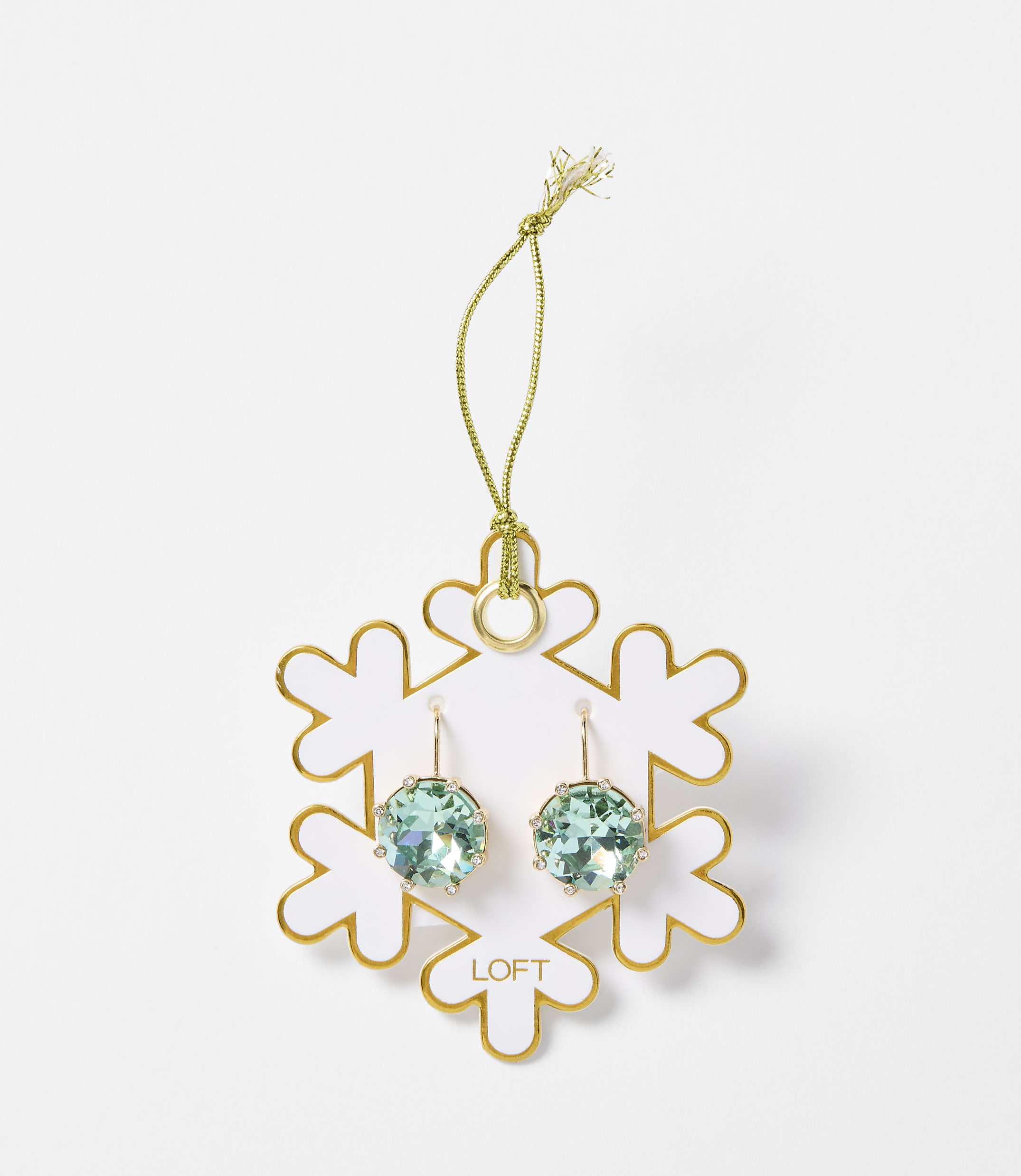 A pair of light blue crystal earrings hang from a gold string attached to a white snowflake ornament with gold trim, set against a plain white background.