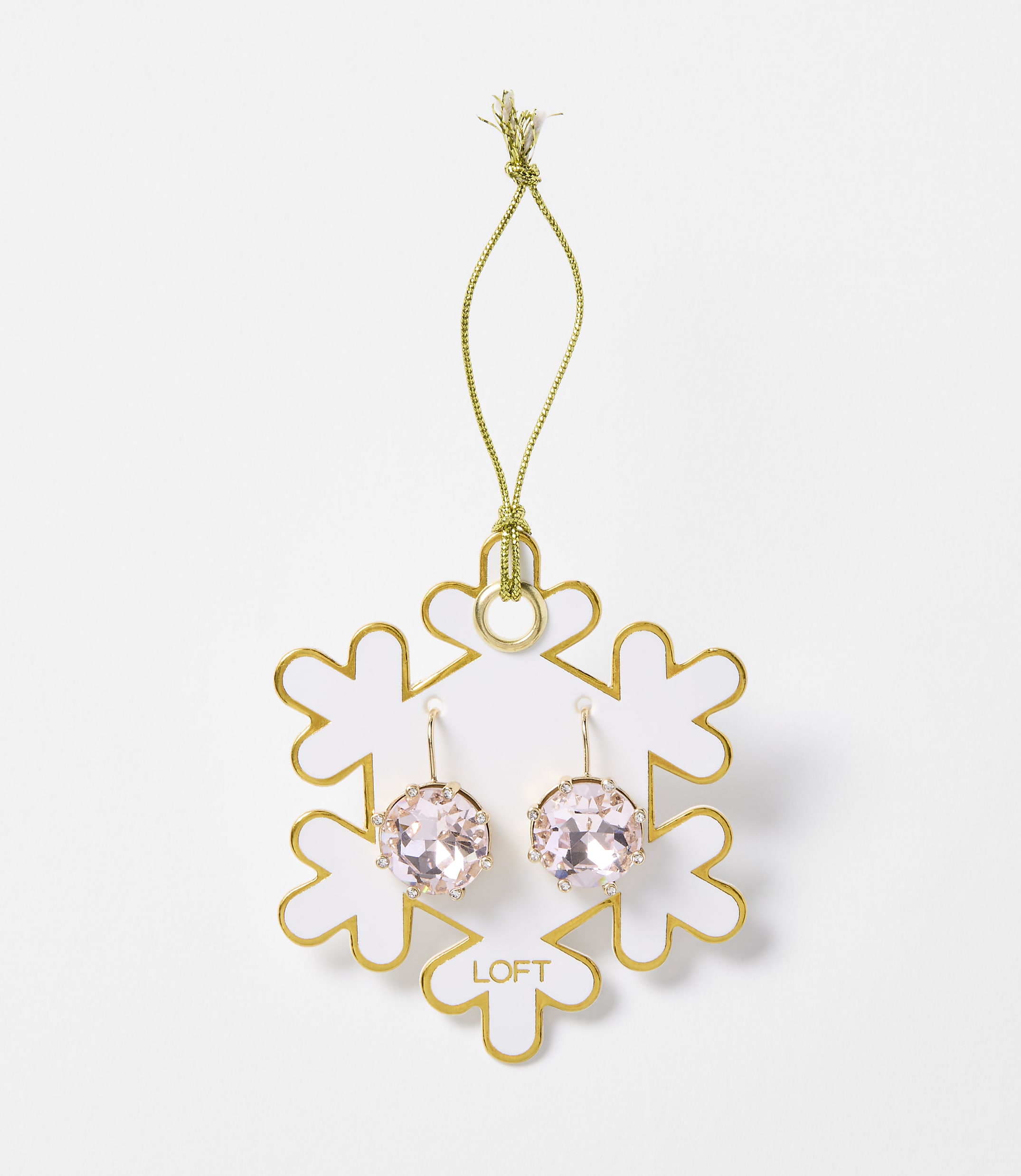 A pair of pink crystal earrings hangs from a gold string attached to a white snowflake ornament with gold trim, set against a plain white background.