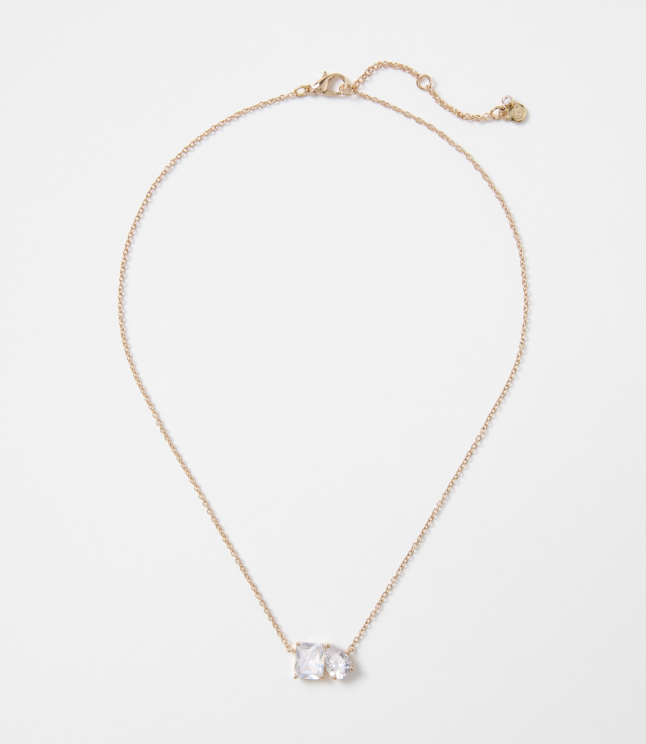 A delicate rose gold necklace with two clear, rectangular stones rests on a plain white background.