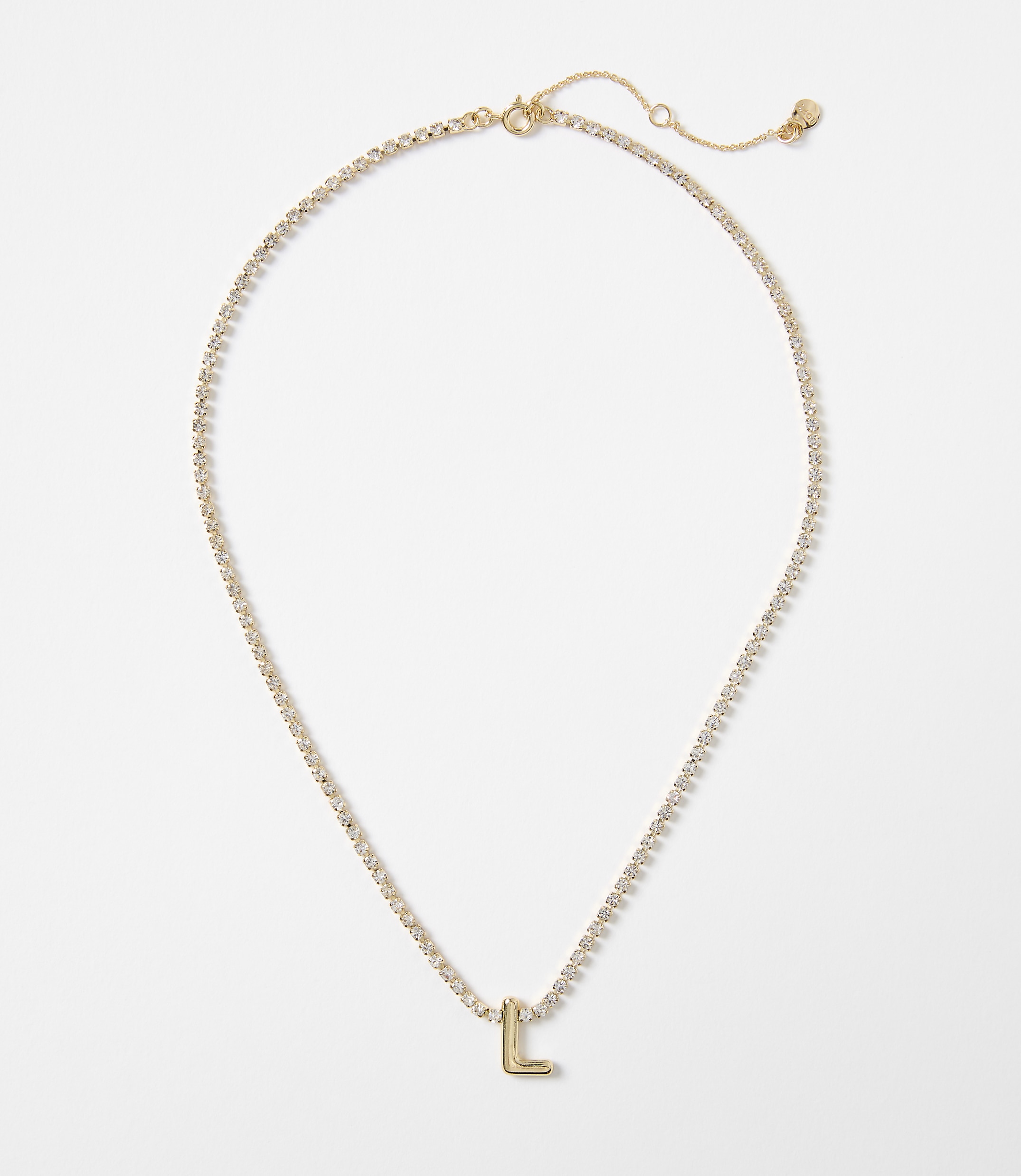 A delicate gold necklace with a sparkling chain and a single letter "L" charm rests on a plain white background.