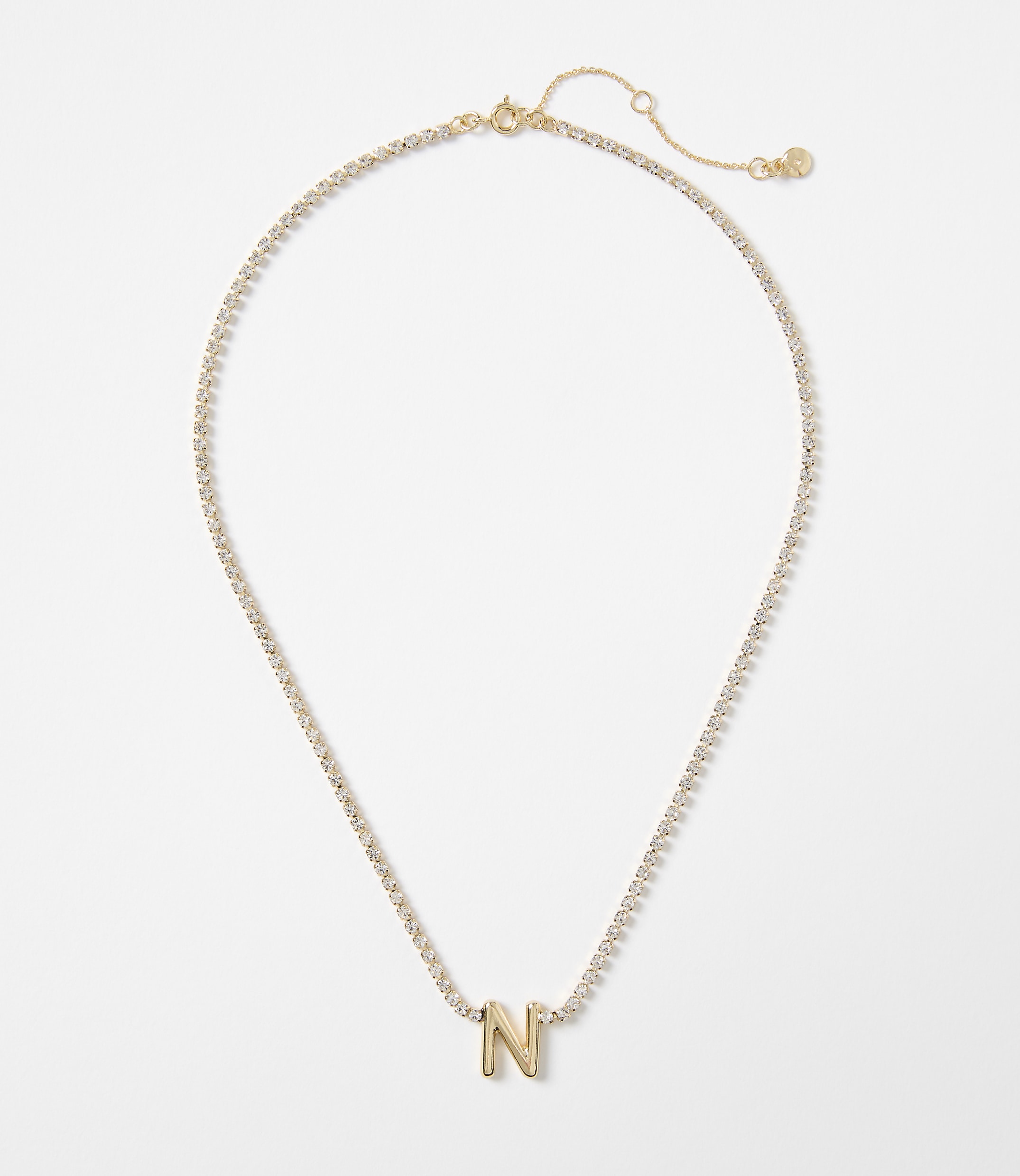 A gold letter "N" charm hangs from a delicate, diamond-encrusted chain against a plain white background.