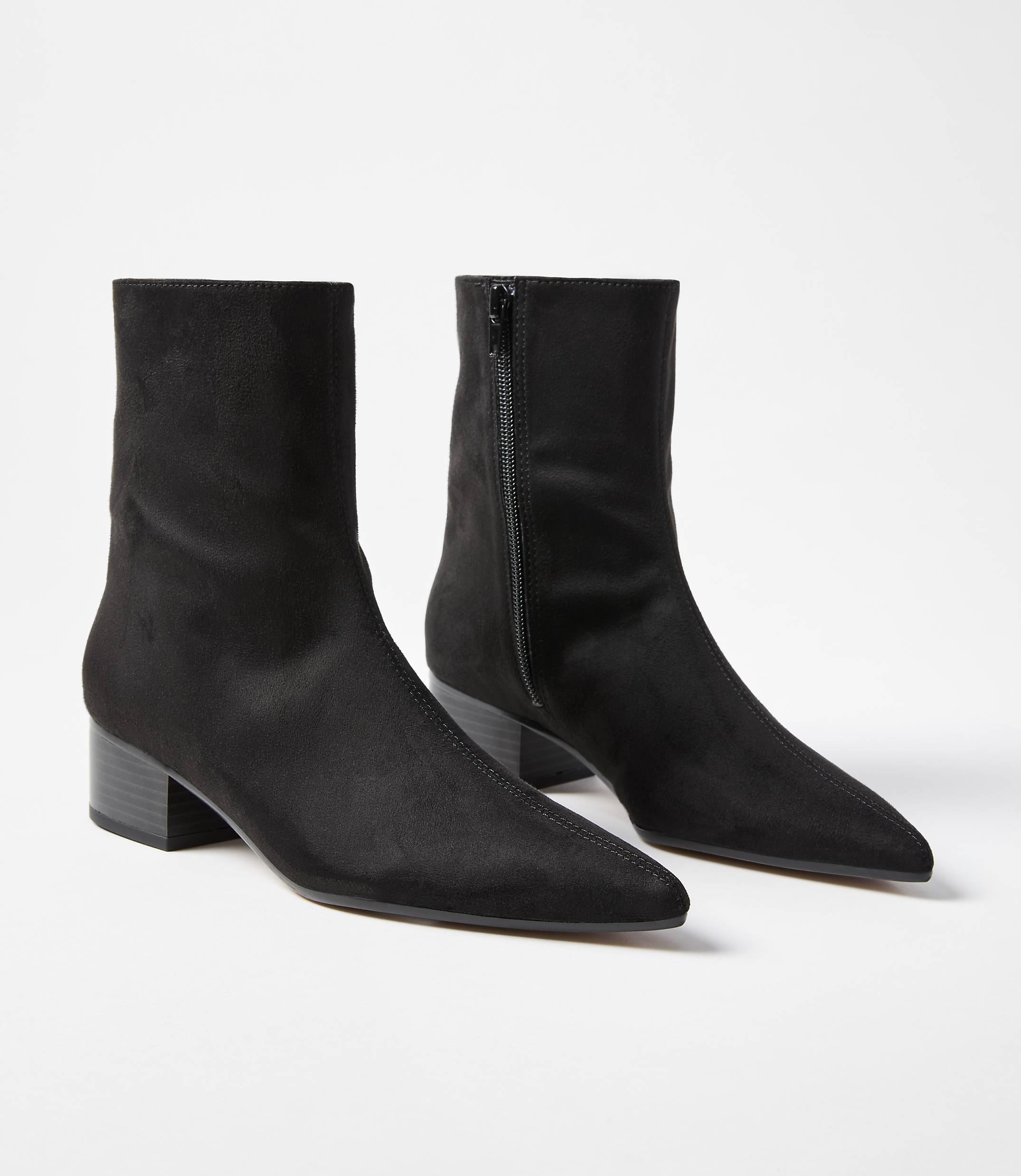 A pair of black pointed-toe ankle boots with block heels are displayed against a plain white background.