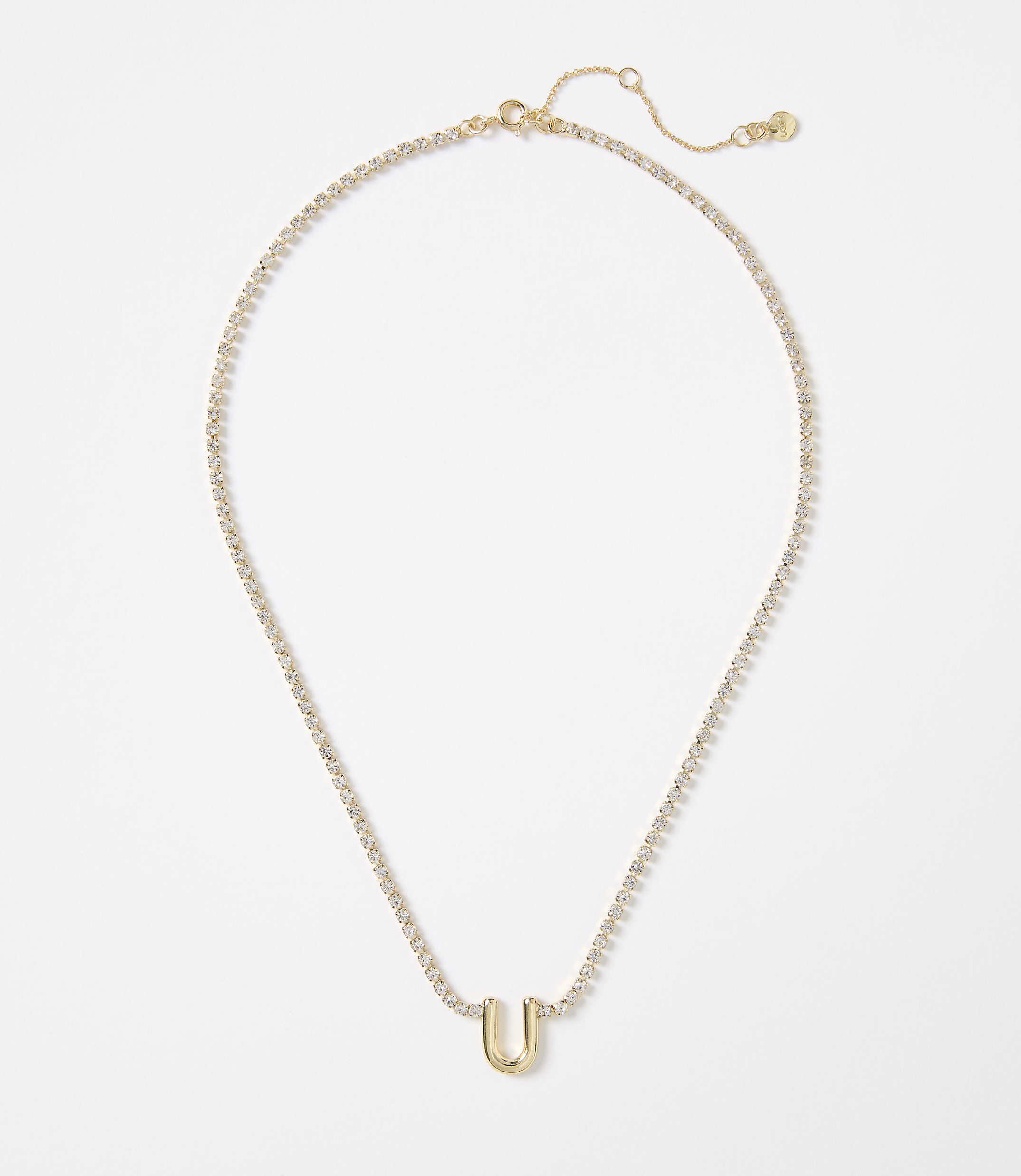 A gold letter "U" pendant hangs from a delicate, diamond-encrusted chain against a plain white background.