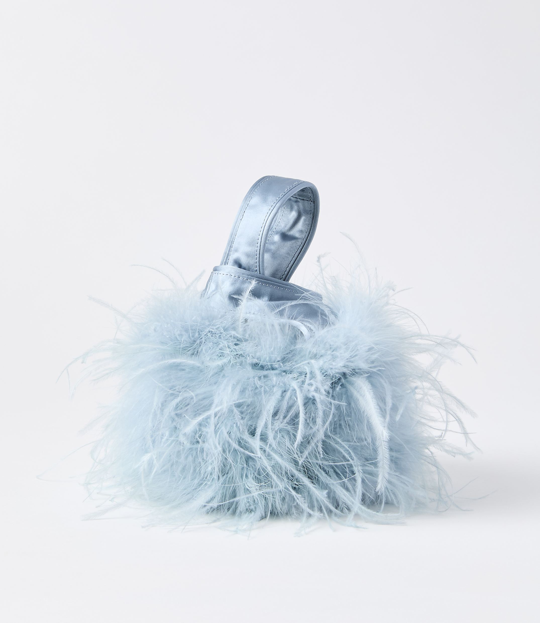 A fluffy, light blue, feather-covered handbag with a satin handle sits against a plain white background.