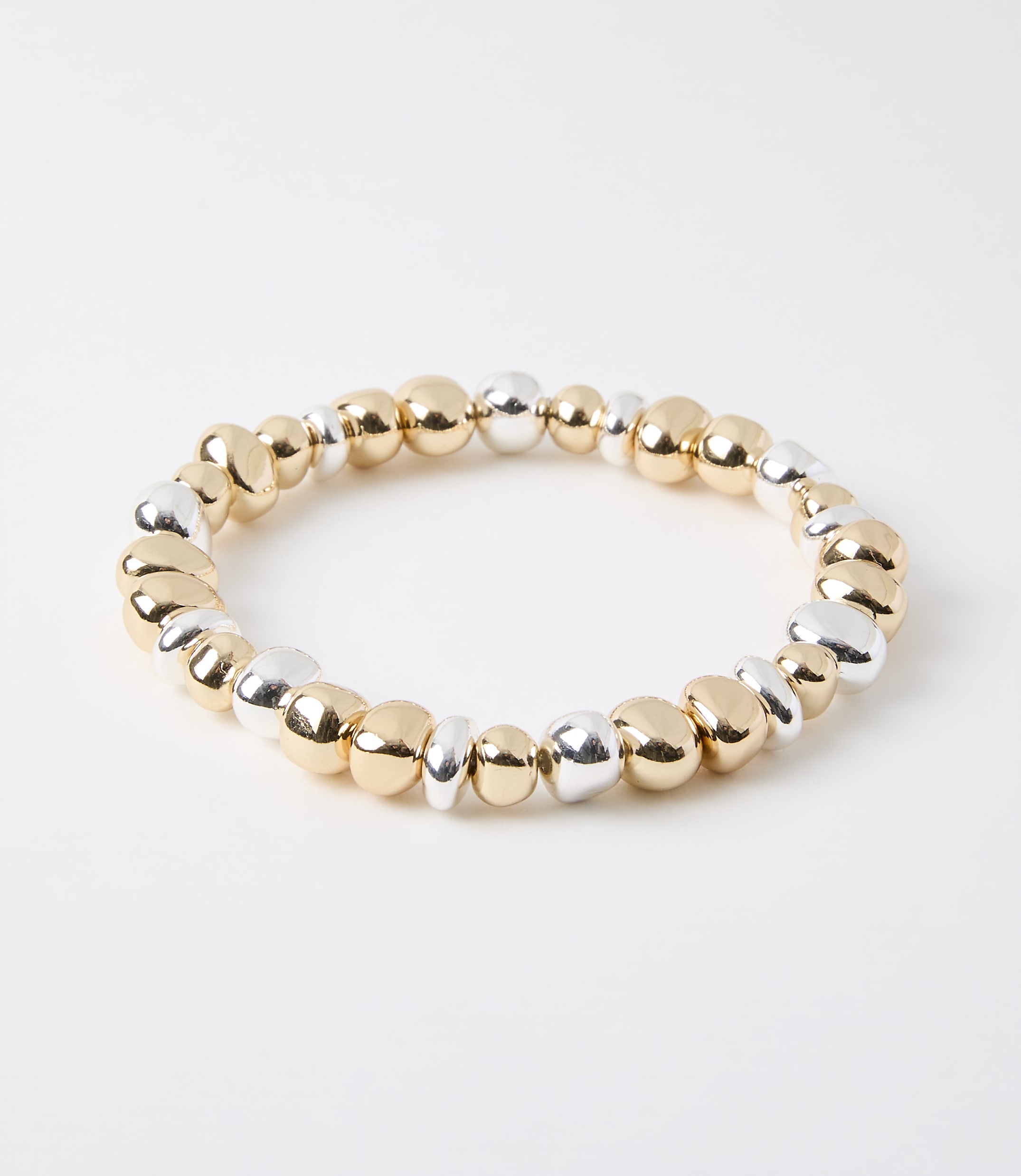 A bracelet of mixed gold and silver beads rests on a plain white background.