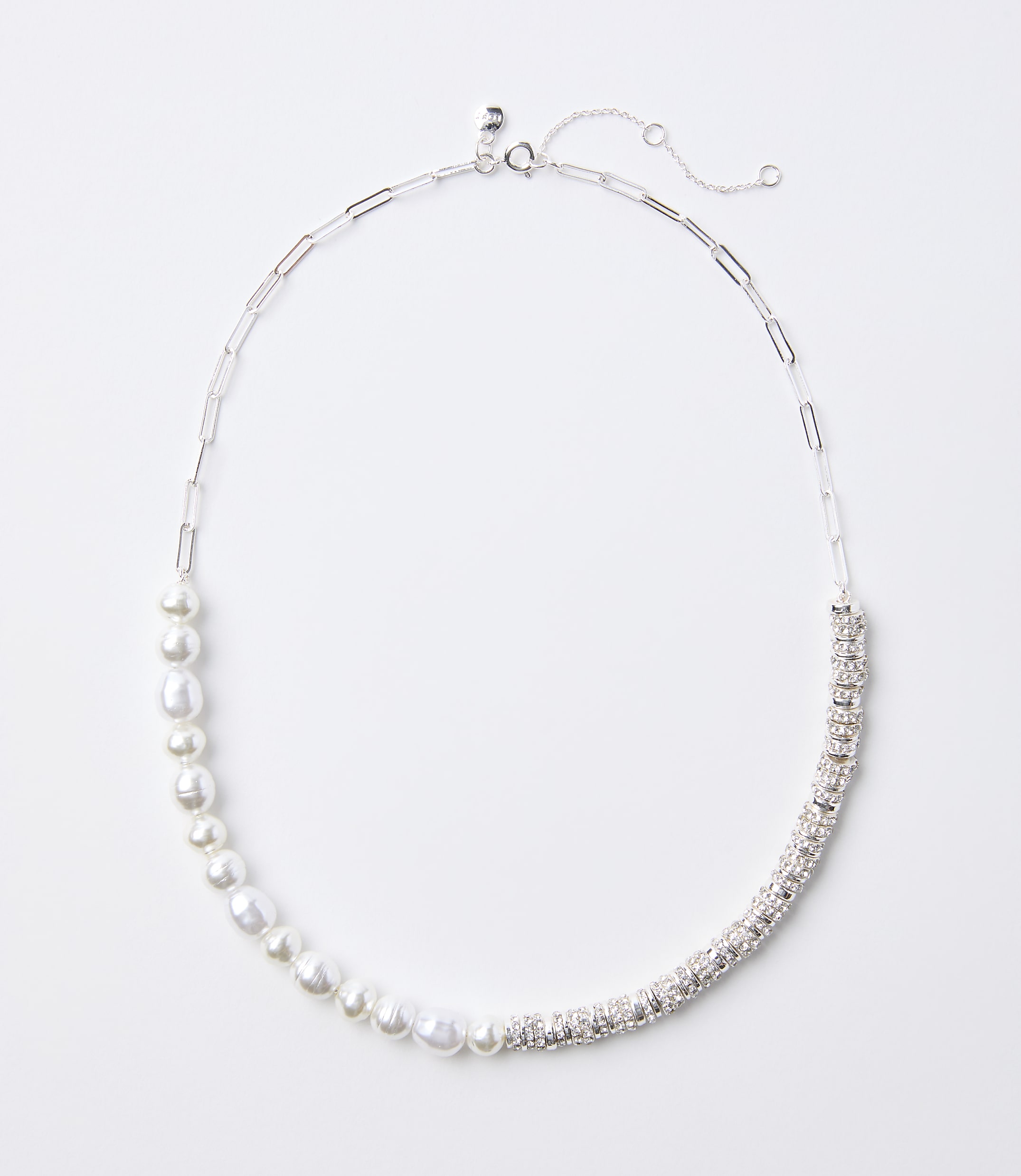 A delicate silver necklace with a chain of pearls on the left and a band of sparkling rhinestones on the right rests on a plain white background.