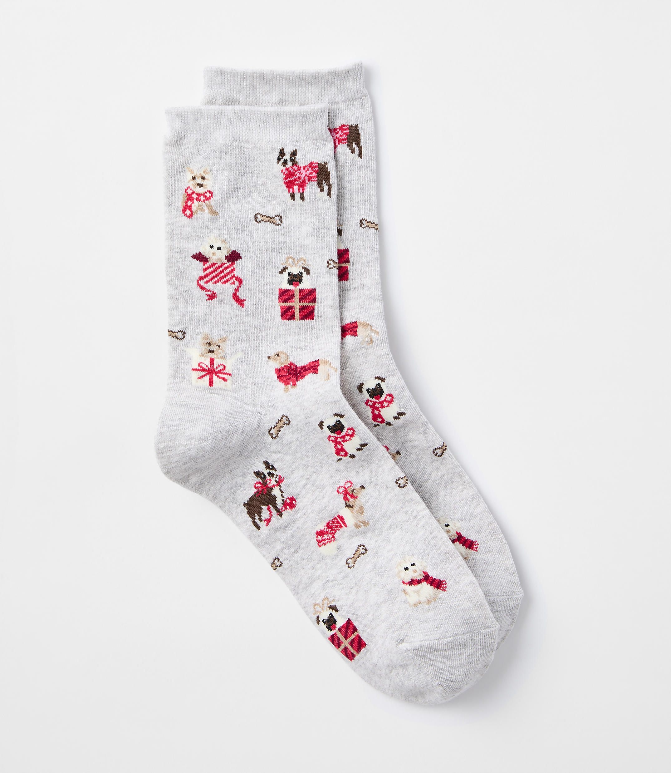 A pair of light gray socks with a pattern of festive dogs wearing sweaters and scarves, along with dog bones and presents, are laid out against a plain white background.
