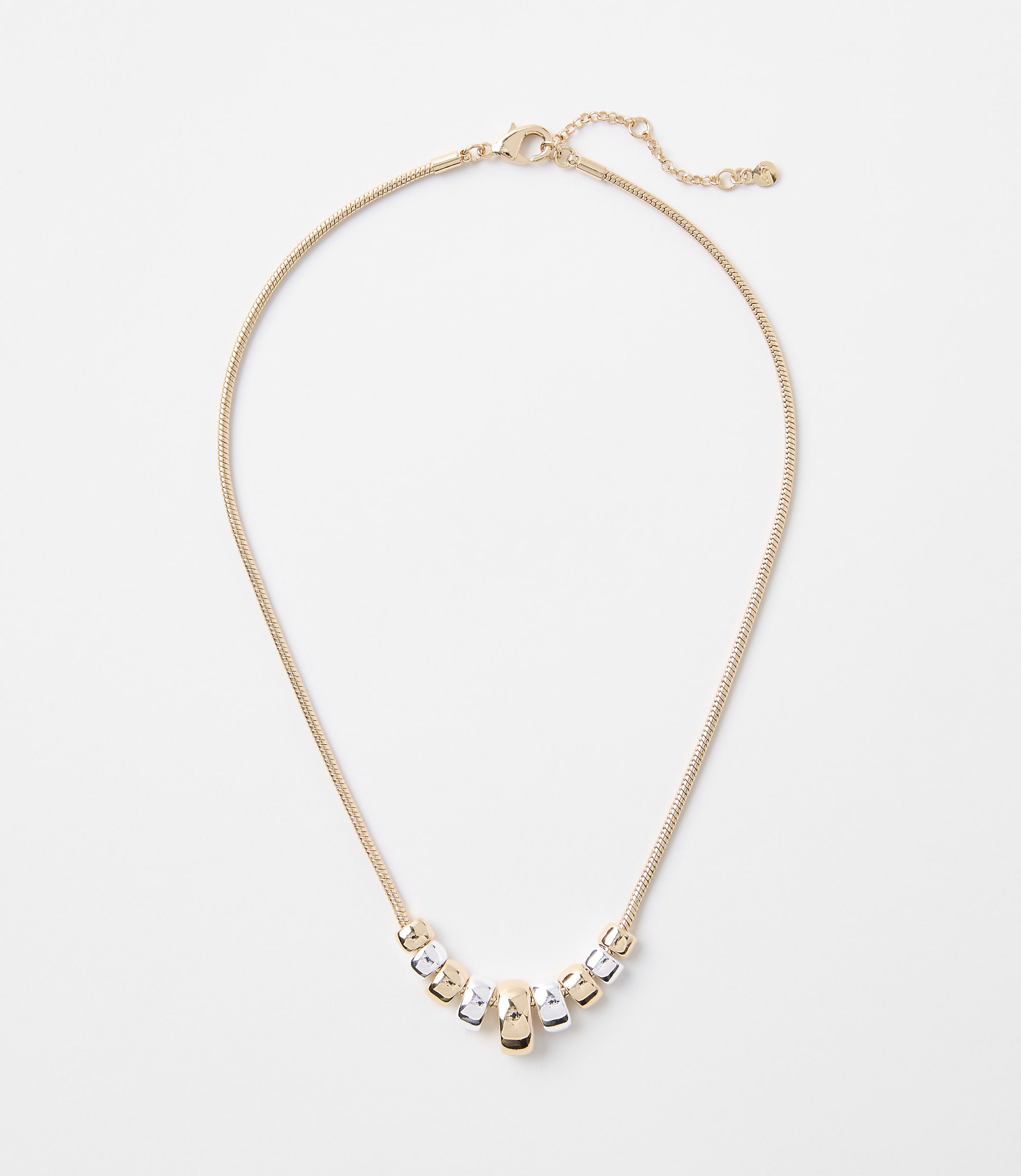 A delicate gold chain necklace with a series of alternating gold and silver cylindrical beads rests on a plain white background.