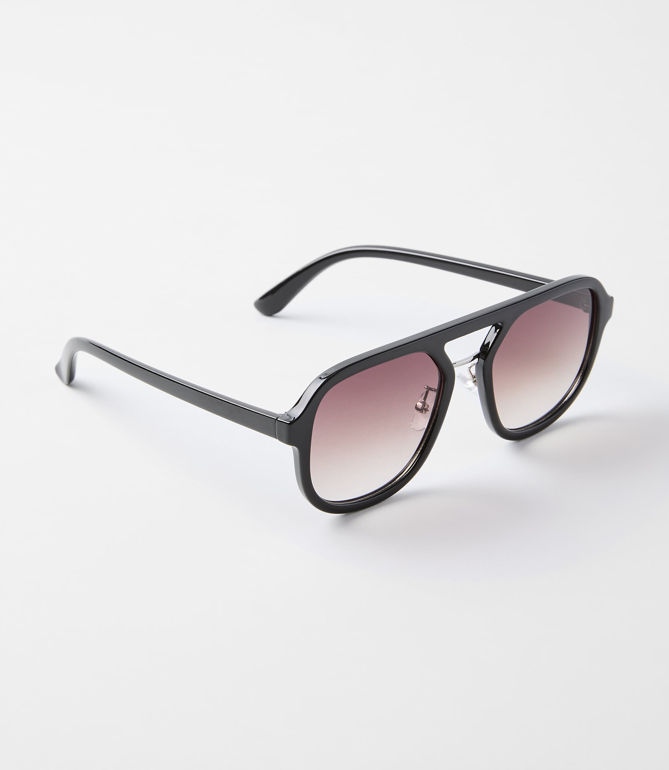 A pair of black aviator sunglasses with gradient lenses rests on a plain white background.