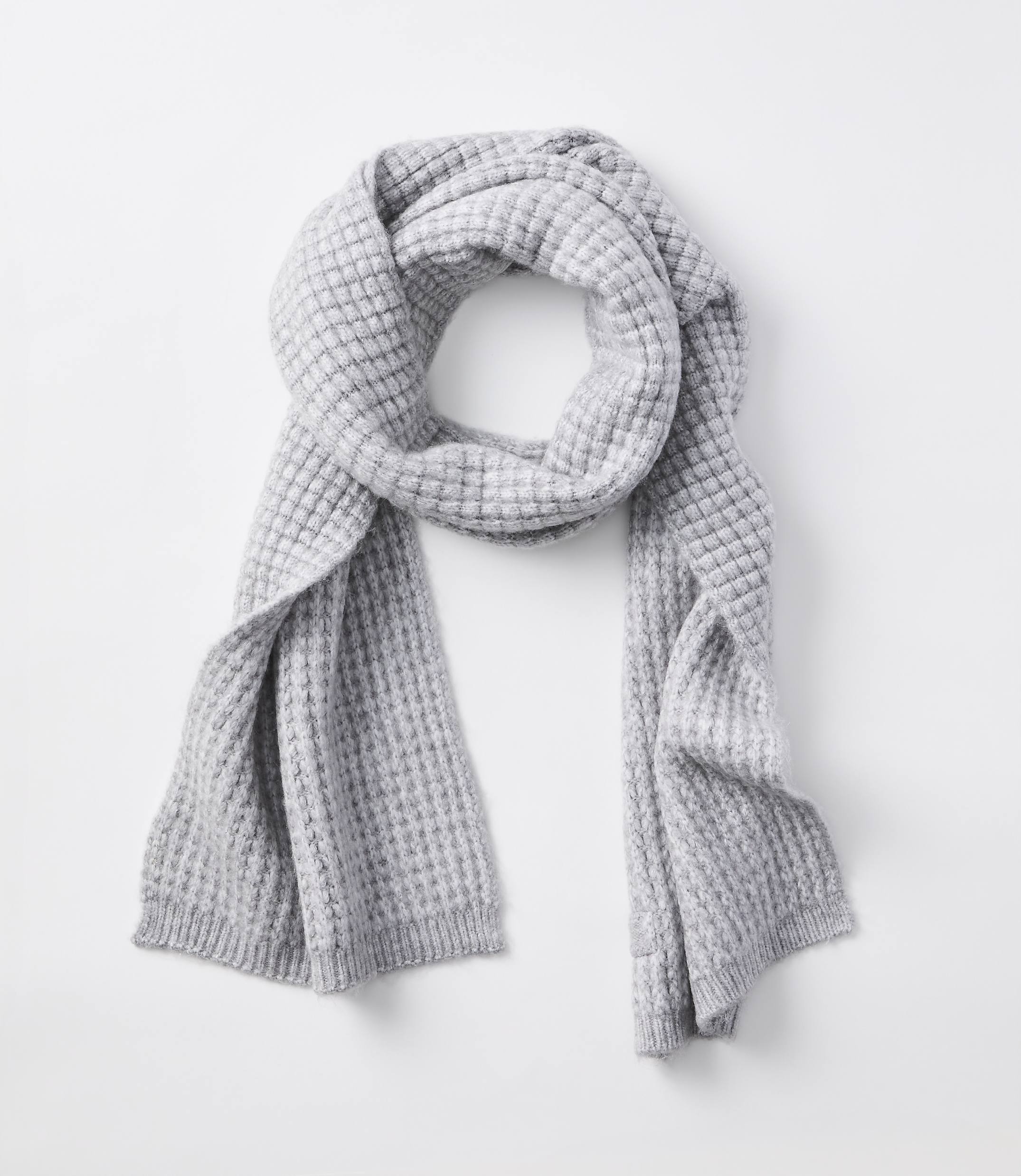 A light gray waffle-knit scarf is draped over a plain white background.