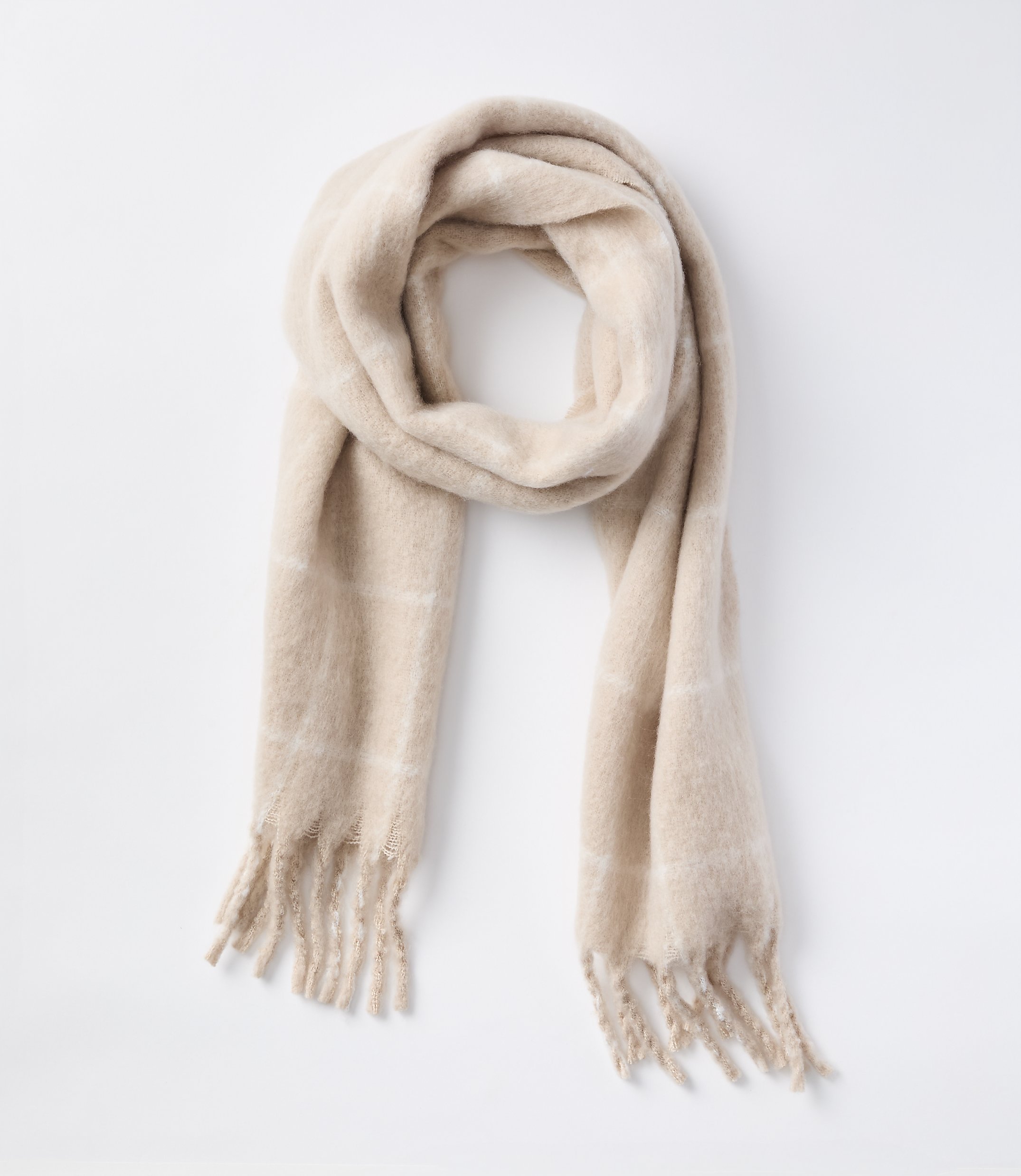 A soft, beige plaid scarf with fringed ends lies draped against a plain white background.