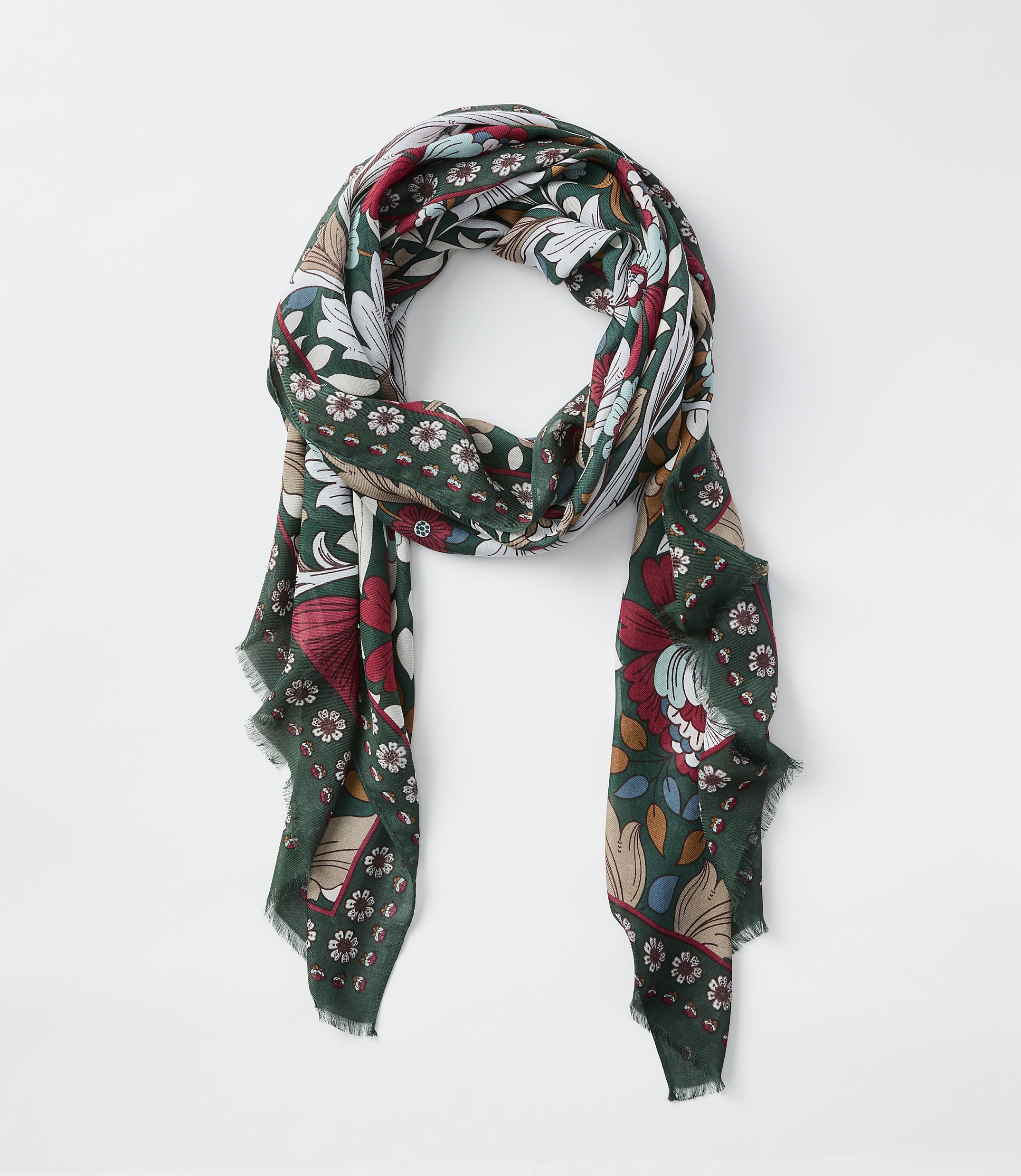 A green scarf with a floral and book pattern hangs against a plain white background.
