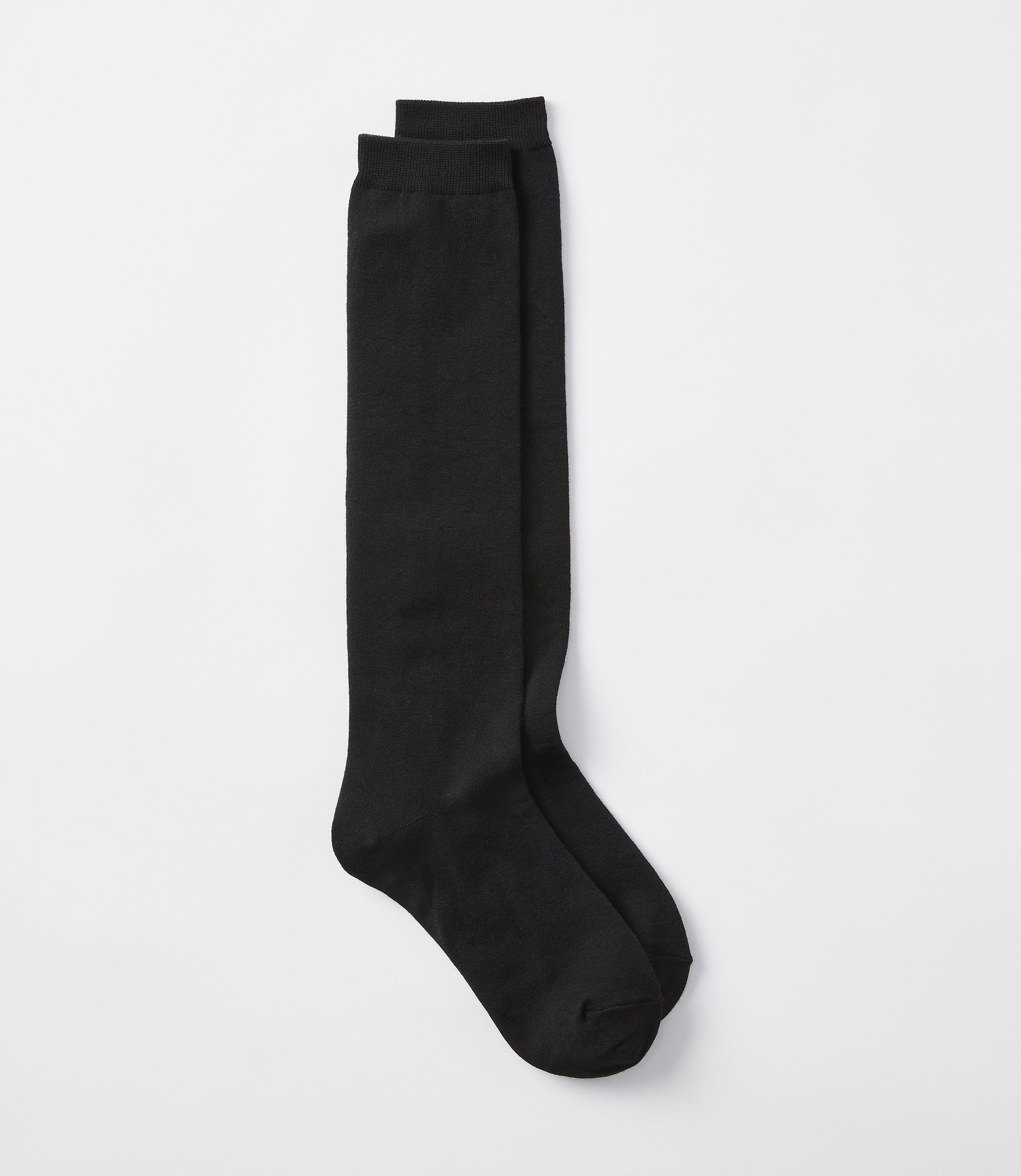 A pair of black knee-high socks lies on a plain white background.