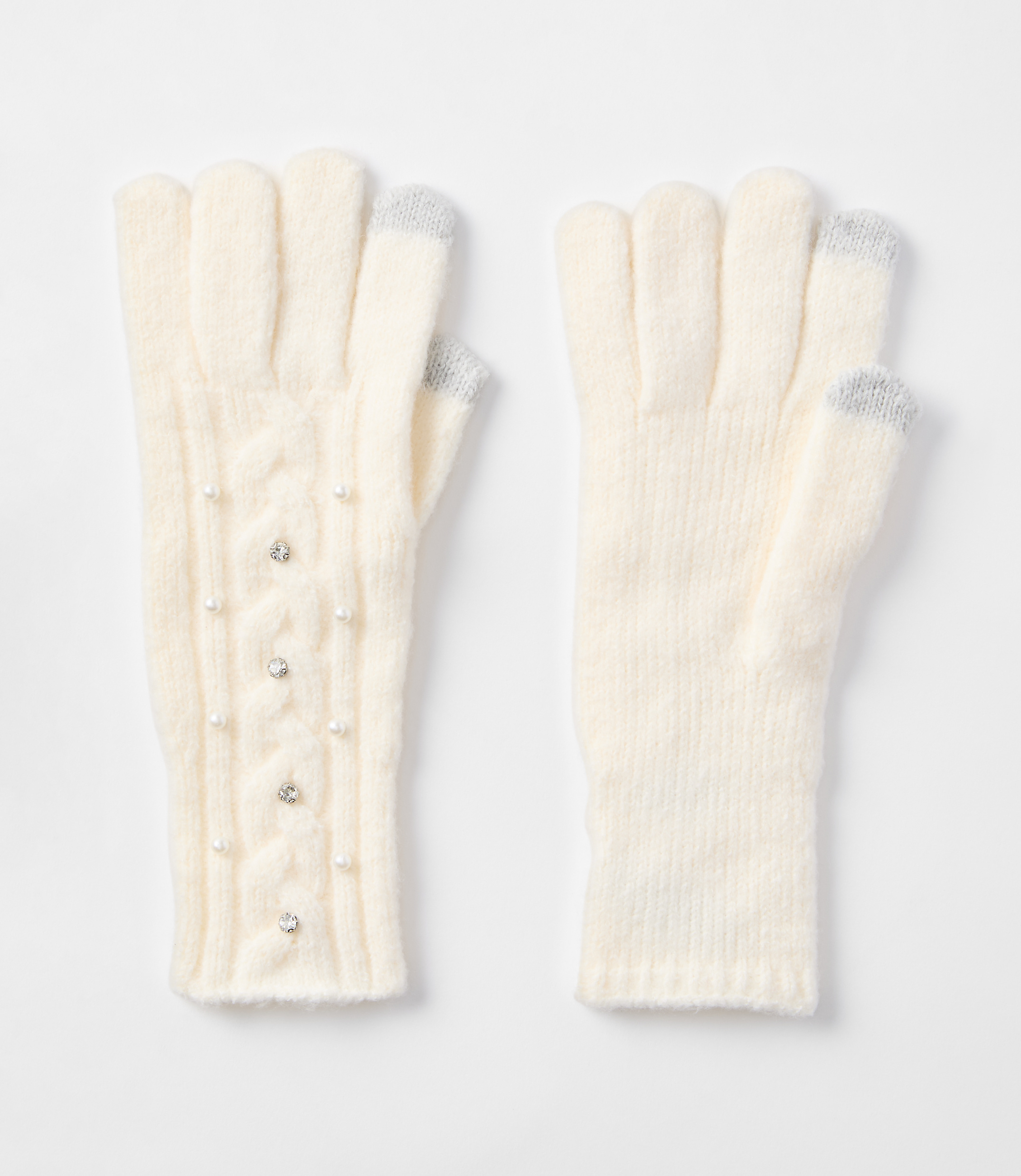Cream-colored knit gloves, one adorned with pearls and rhinestones, rest on a plain white background.
