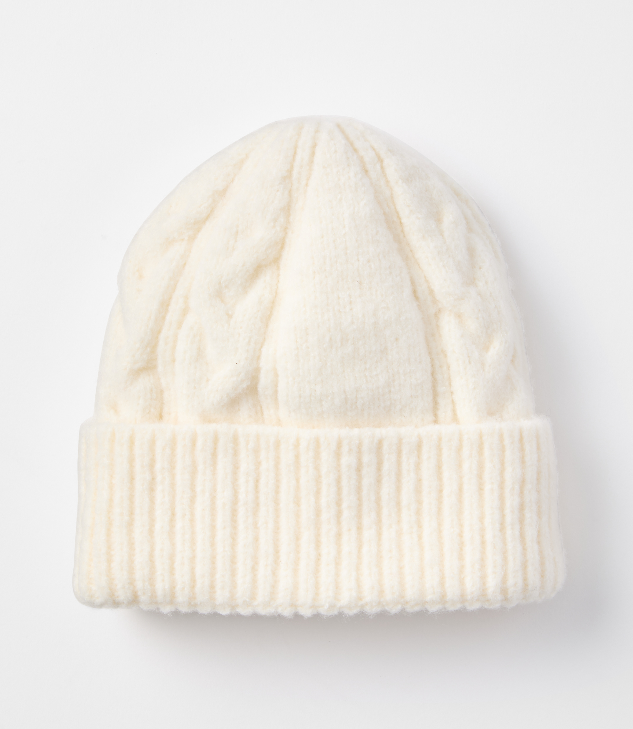 A cream-colored cable-knit beanie with a ribbed cuff rests on a plain white background.
