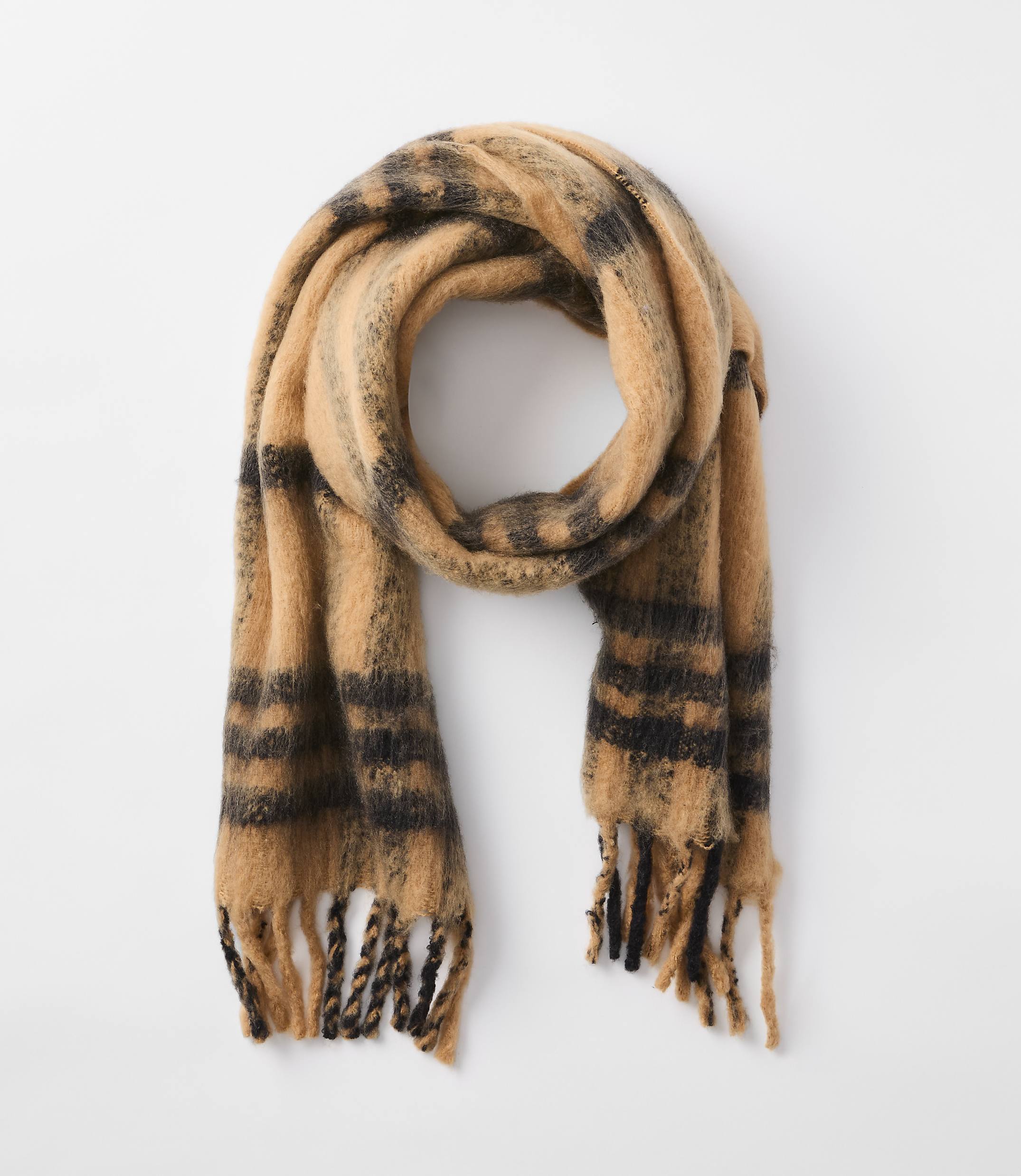 A fuzzy, tan and black striped scarf with fringed ends hangs against a plain white background.