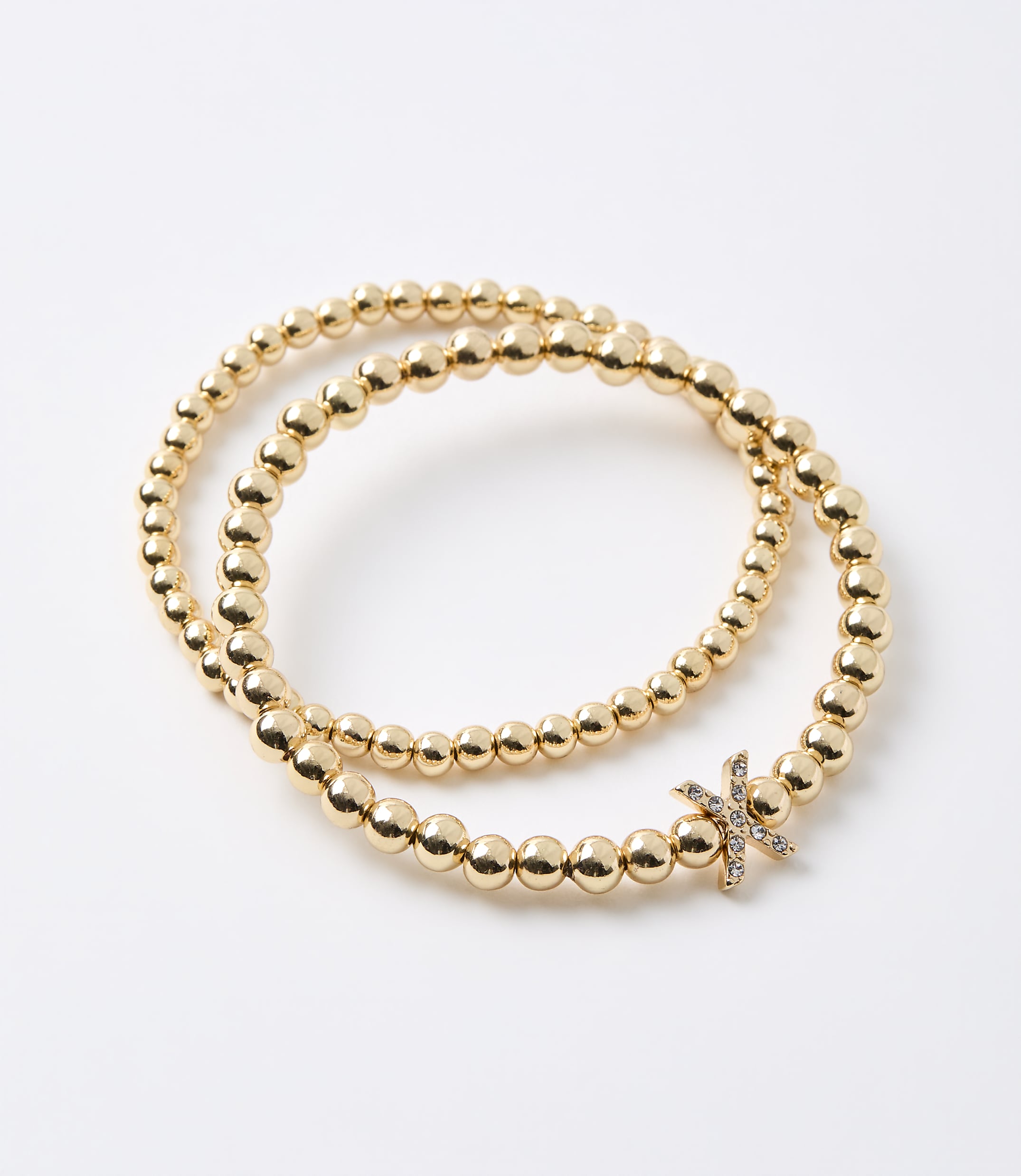 Two gold beaded bracelets, one with a diamond-studded initial "K" charm, are arranged on a plain white background.