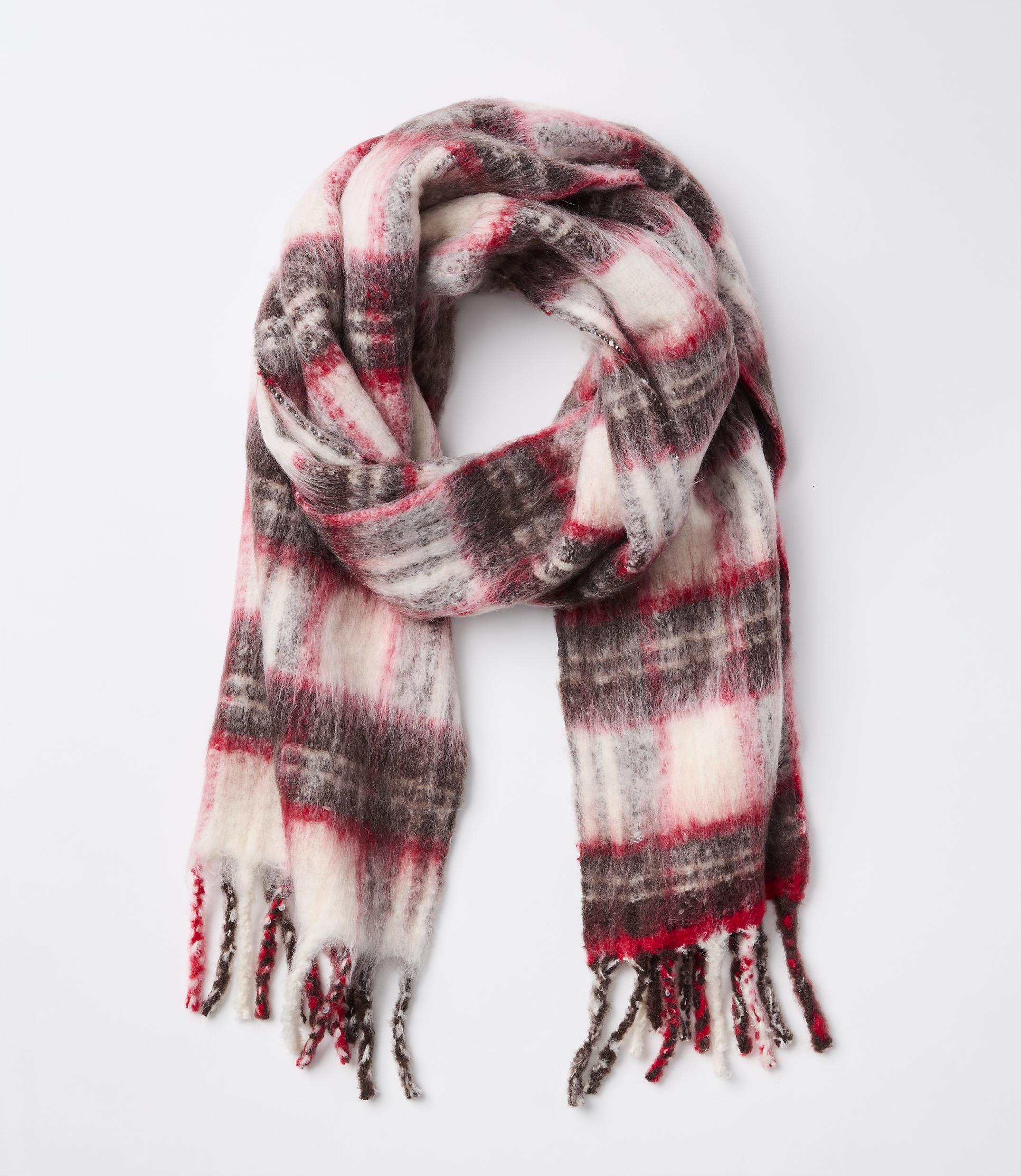 A fluffy, plaid scarf with red, white, and brown colors is laid out against a plain white background.
