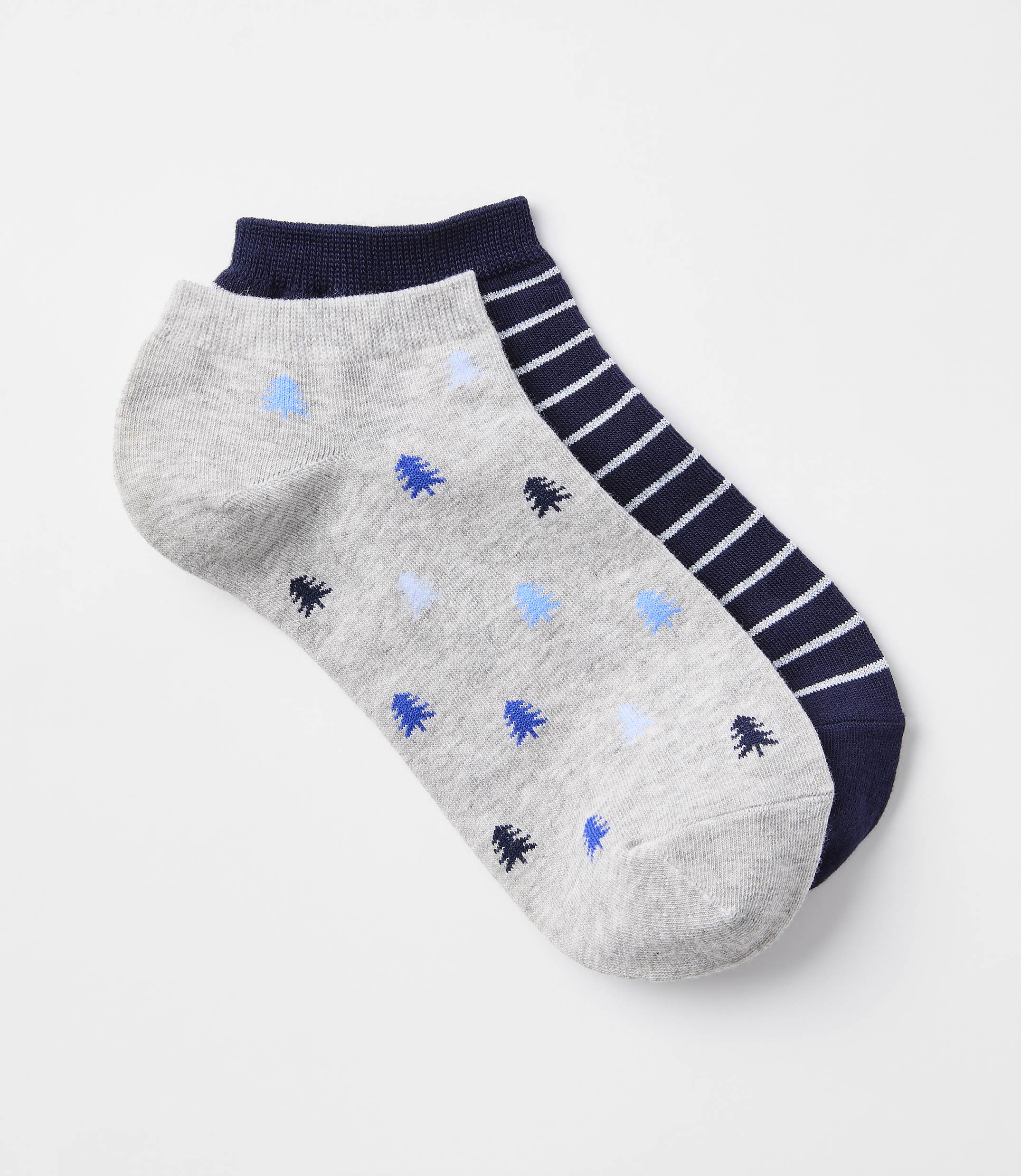 A pair of ankle socks, one with a gray background and blue tree pattern, and the other with navy and white stripes, rests on a plain white background.