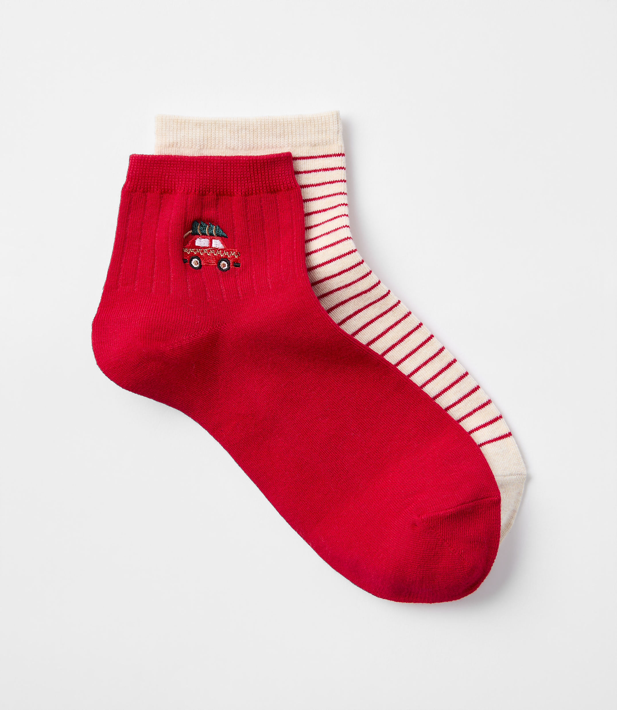 A pair of red socks, one with a small embroidered car and the other with red stripes, are laid out against a plain white background.