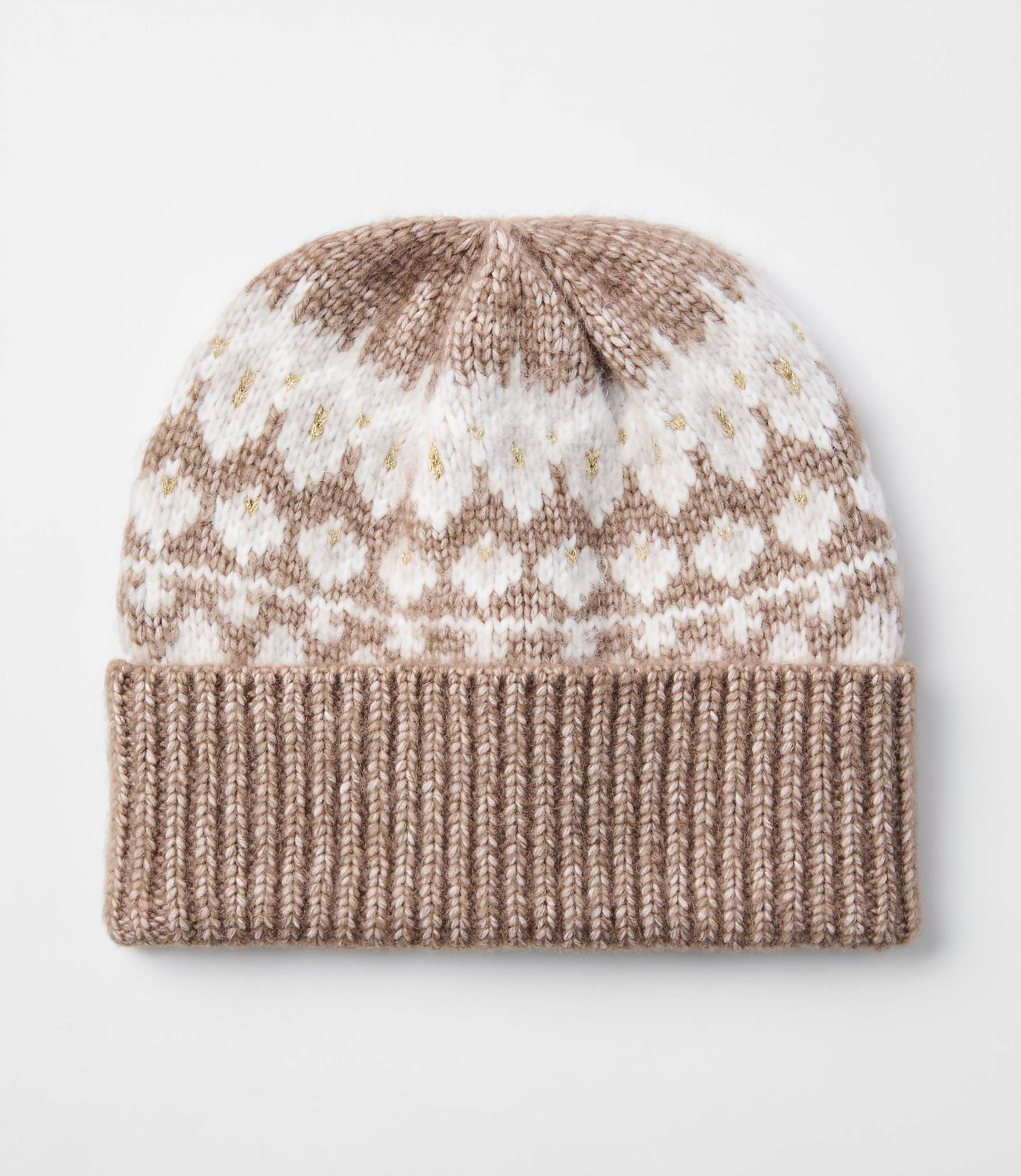 A knitted beanie with a ribbed brim in a light brown color is in the foreground, while the background is a plain white surface.