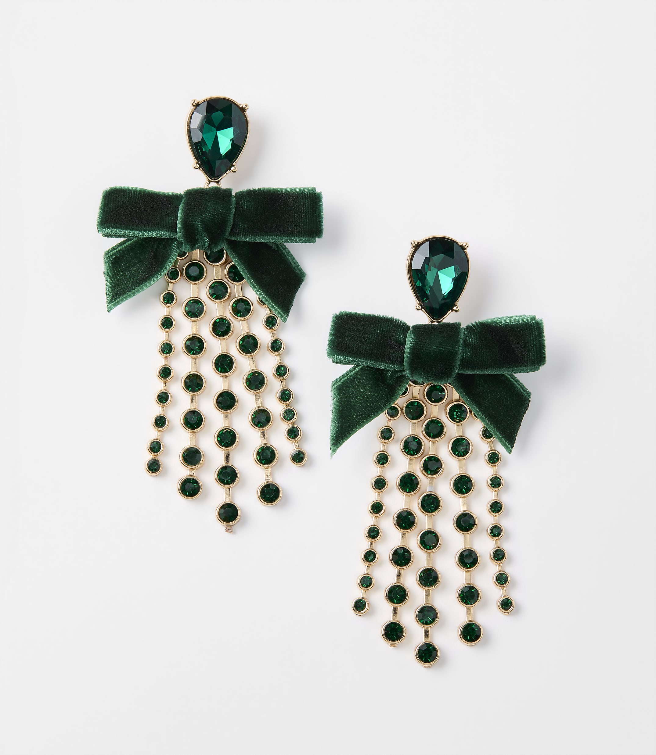A pair of emerald green velvet bow earrings with dangling jeweled fringe are displayed against a plain white background.