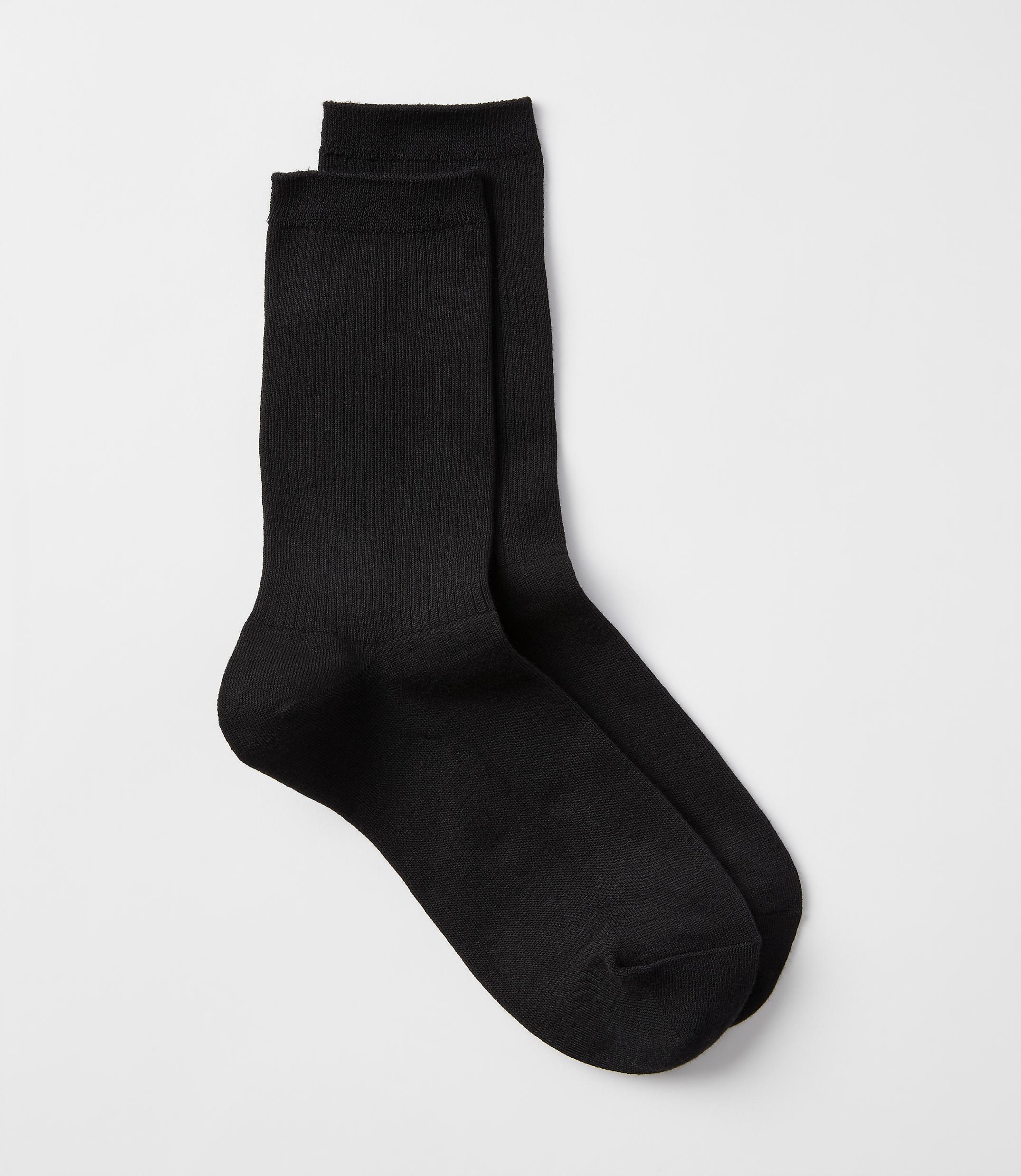 A pair of black ribbed socks rests on a plain white background.