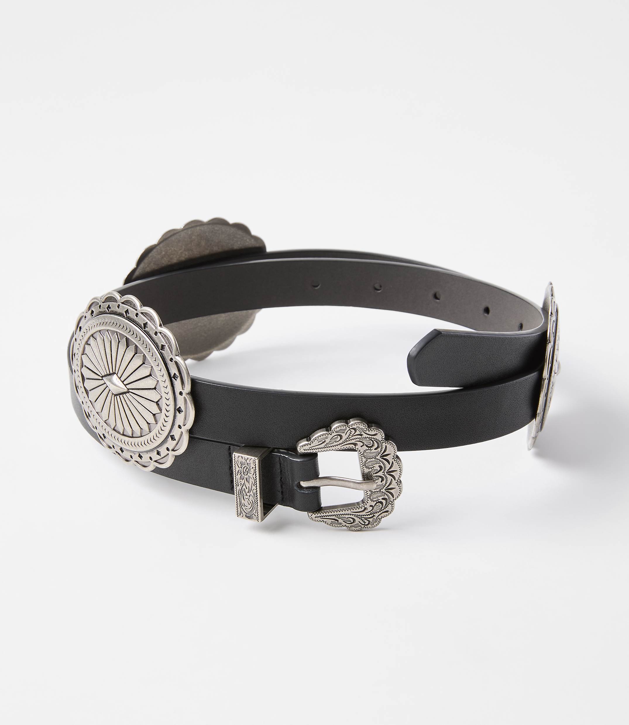 A black leather belt with ornate silver concho embellishments and a buckle rests against a plain white background.