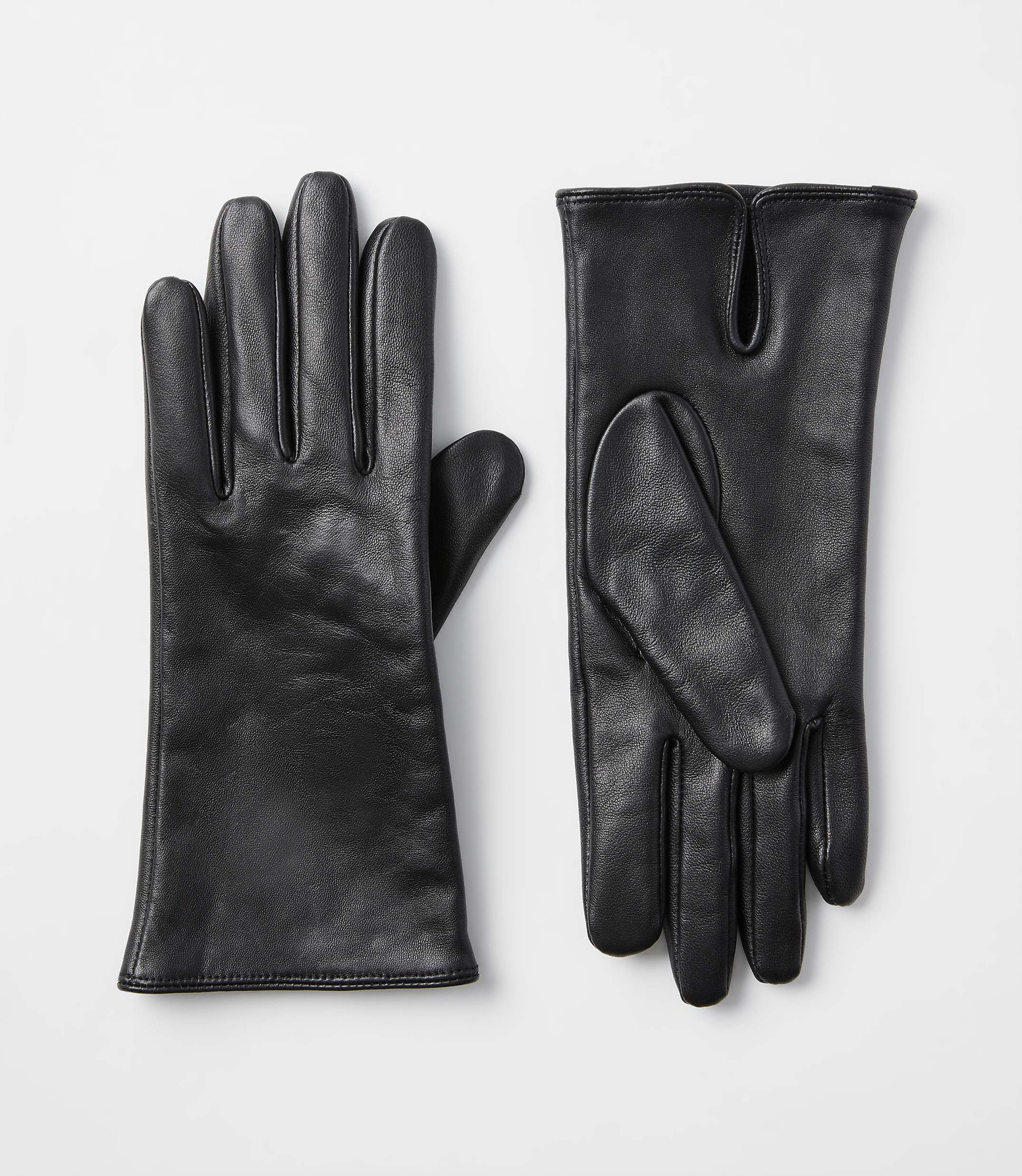 A pair of black leather gloves lies on a plain white background.