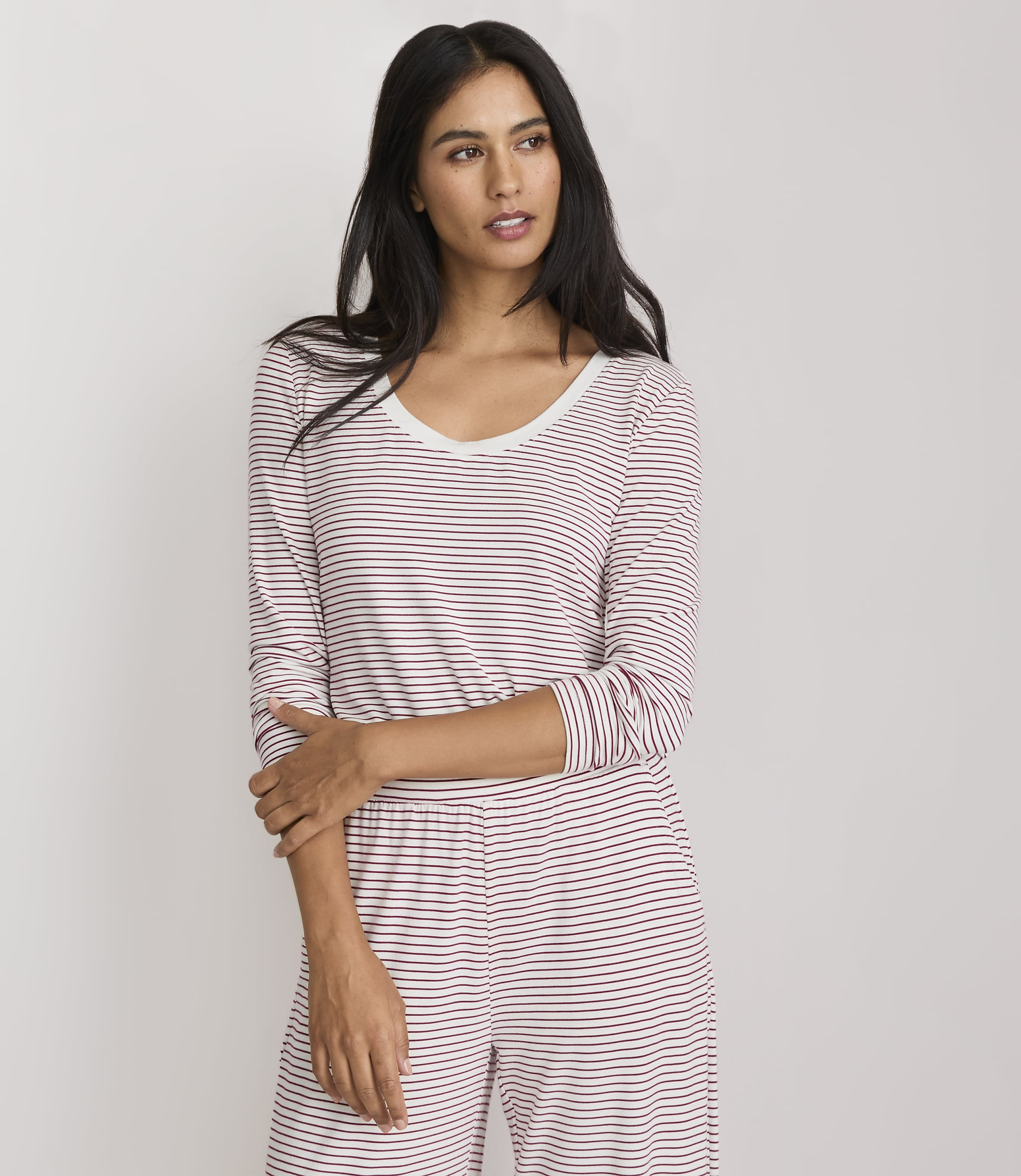 A woman in a striped pajama set stands against a plain white background.