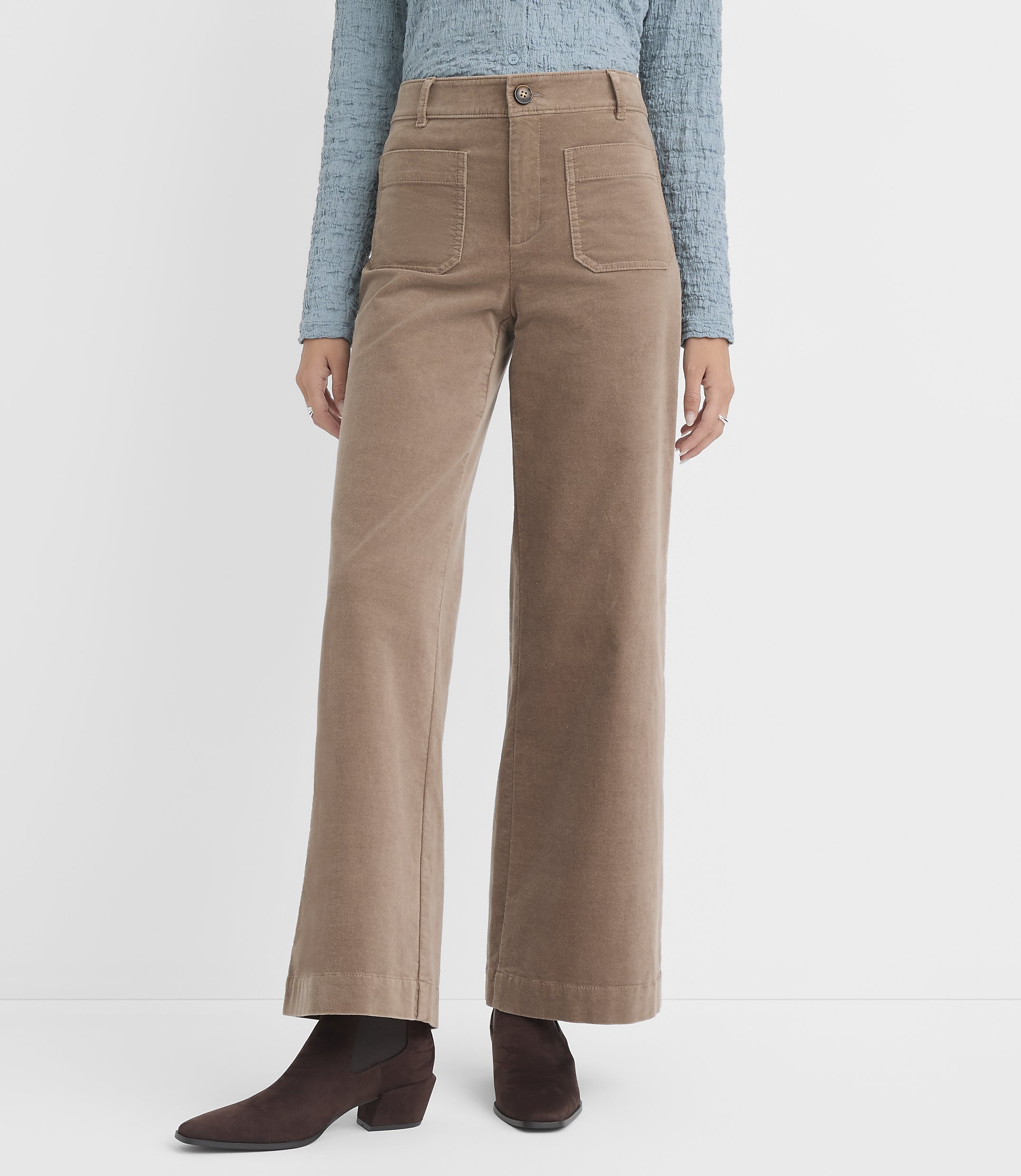 A person wearing tan corduroy wide-leg pants and brown boots stands against a plain white background.