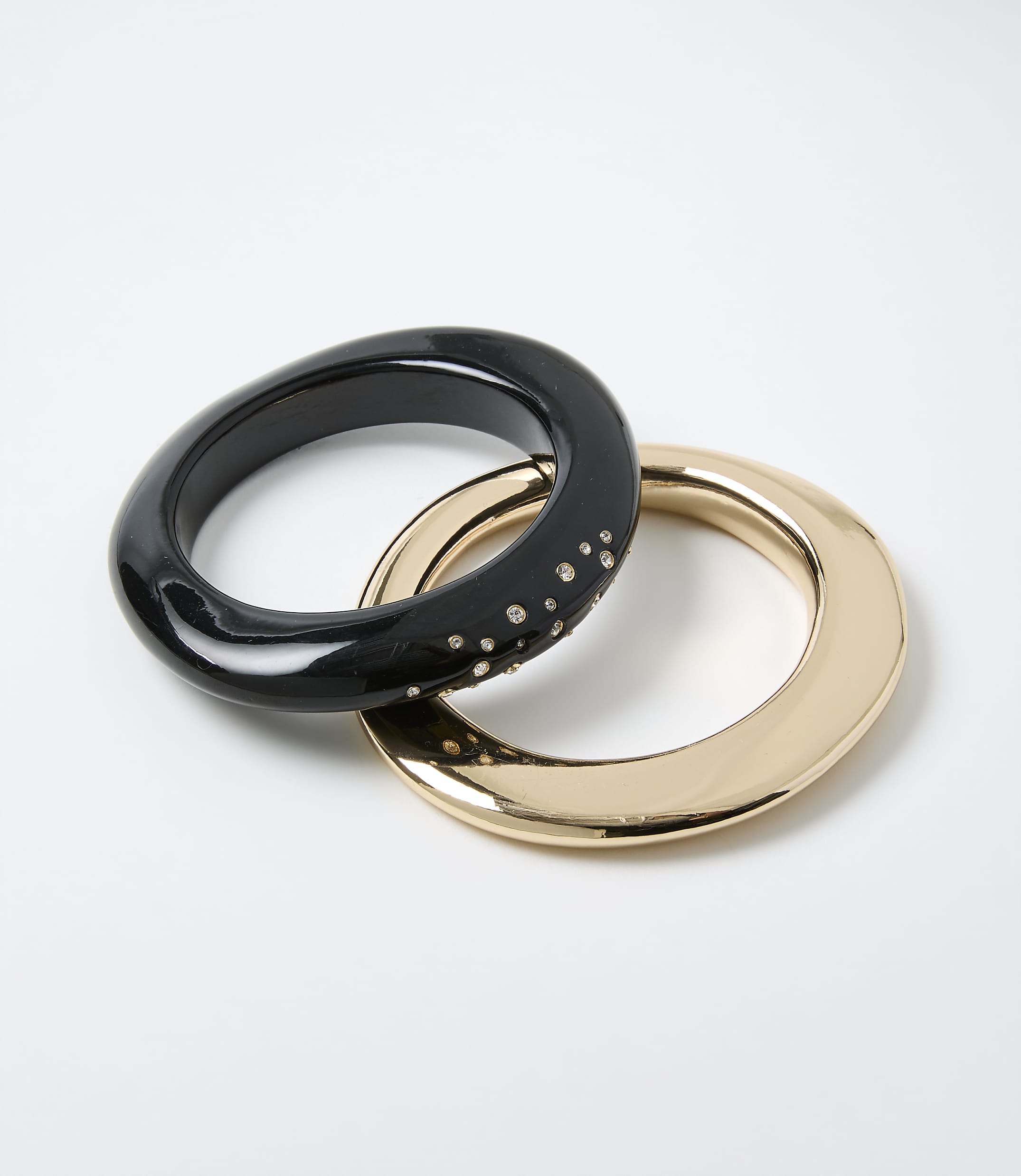 Two interlocking rings, one black with small crystals and one gold, rest on a plain white background.
