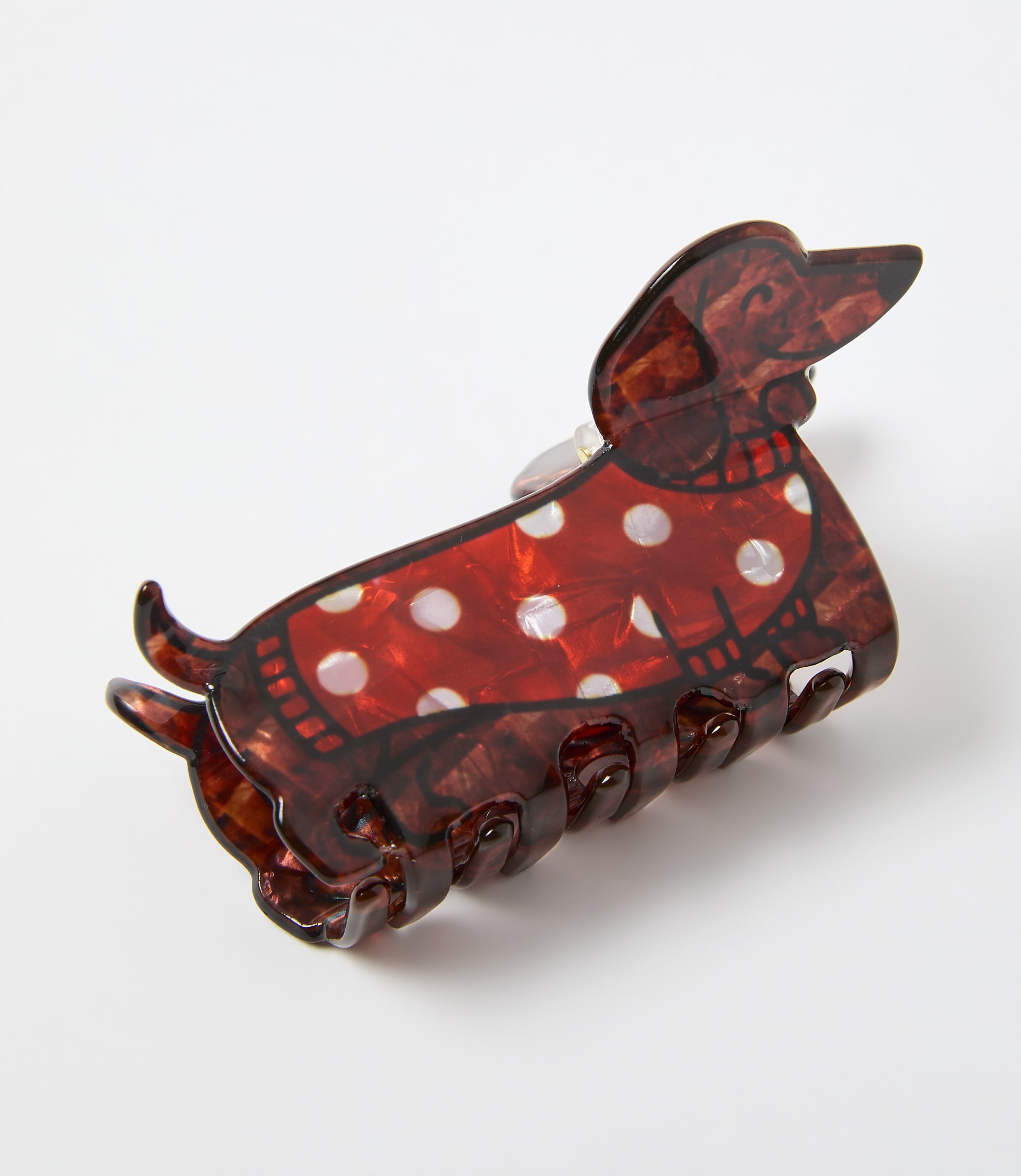 A red and white polka-dotted dachshund hair claw clip rests on a plain white background.