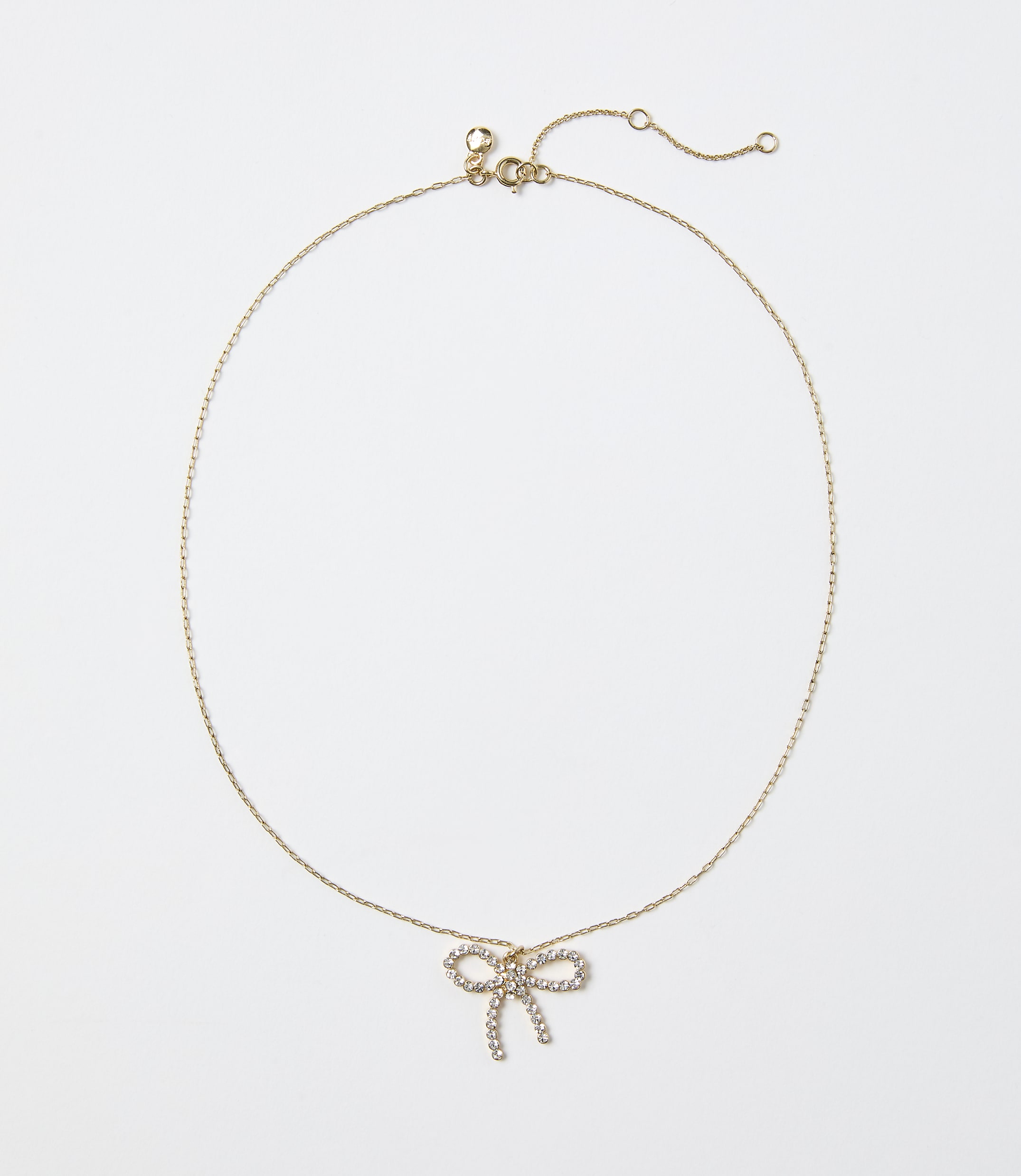 A gold chain necklace with a diamond-encrusted bow pendant rests against a plain white background.