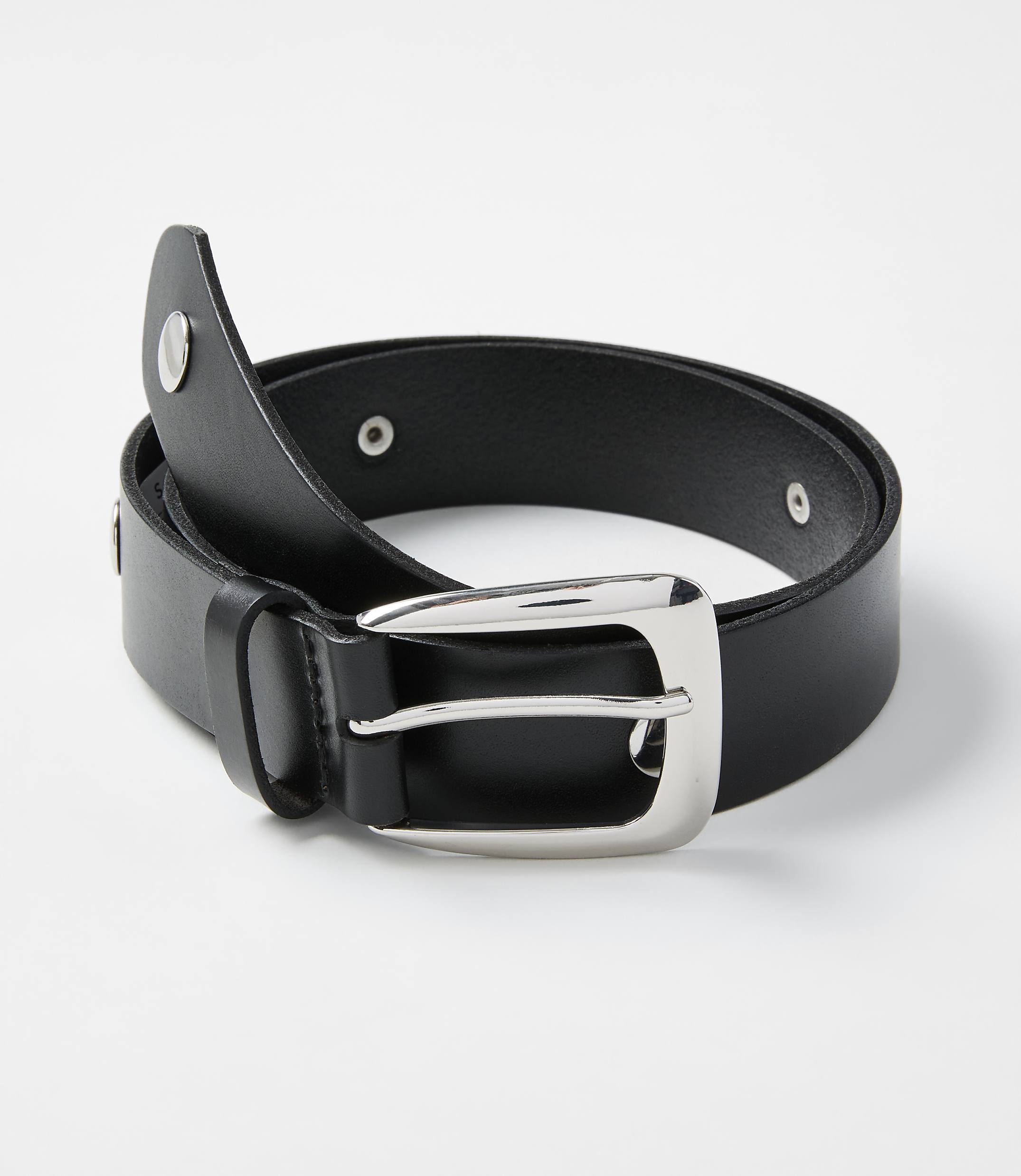 A black leather belt with a silver buckle is coiled on a plain white background.