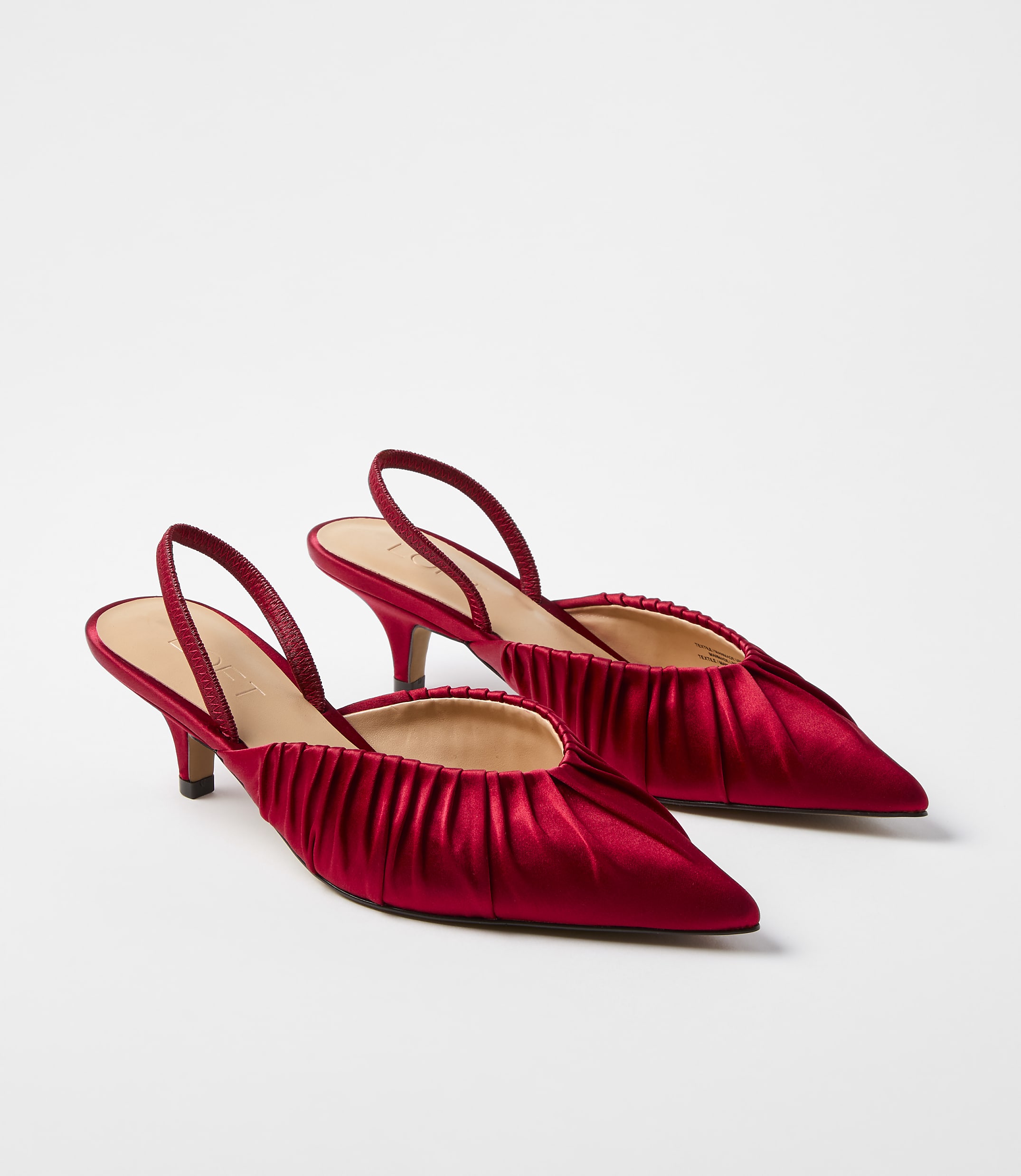 A pair of red satin slingback heels with pleated toes sits against a plain white background.